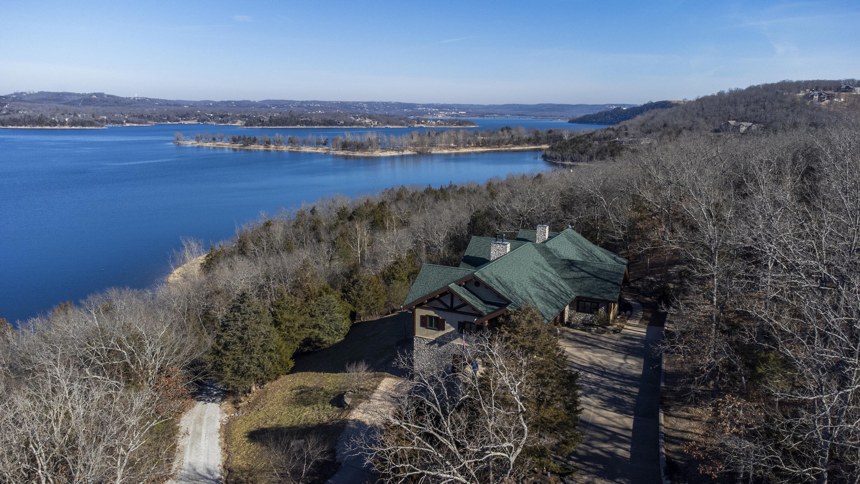 Breath taking views coupled with masterful designed custom estate.  Nestled on over 6 acres of gentle slopped, walk to the waters edge lake front land and behind the gates of the subdivision is this over 8000 square foot partial log home with plenty of space for all the family and friends.  Two large 1080 square foot garages with plenty of space for all your toys and then some.  Walk into the front door to a massive great room and open kitchen.  Towering full log vaulted ceiling with floor to ceiling windows.  All stone wood burning fireplaces in the great room, down stairs living room and master bedroom.  Master bedroom, kitchen, laundry, dining and additional bedroom all on main level.  Step out on the main deck (1256 square feet) for expansive views of Table Rock Lake.  Sit in your hot tub or entertain from your outdoor kitchen.  Want to sit and have coffee and listen to nature and watch the sun come up then step out onto your 200 square foot screened in sunroom.  Custom wood throughout.  Meticulously maintained home and grounds.  Find your way downstairs to your living room outfitted with your own custom burl wood pool table, 50's style diner booth and fully functioning soda fountain and ice cream bar.  Two more bedrooms and bathrooms found on this level.  Also on this level you will find a large storage area and 100 square foot vault/storm shelter protected with Fort Knox vault door.  Also down here you will find another 1080 square foot garage.  Step out on this glorious 828 square foot deck and unwind. This home is being sold mostly furnished with high end furnishings and appliances.  Of course no lake house is complete without a dock close and a slip available and this  home has both.  12x30 slip is available for extra money and does include a lift.  This estate is one of the finest on the lake and is in one of the friendliest subdivisions as well.  Call today to schedule your private showing of this lake dream home.