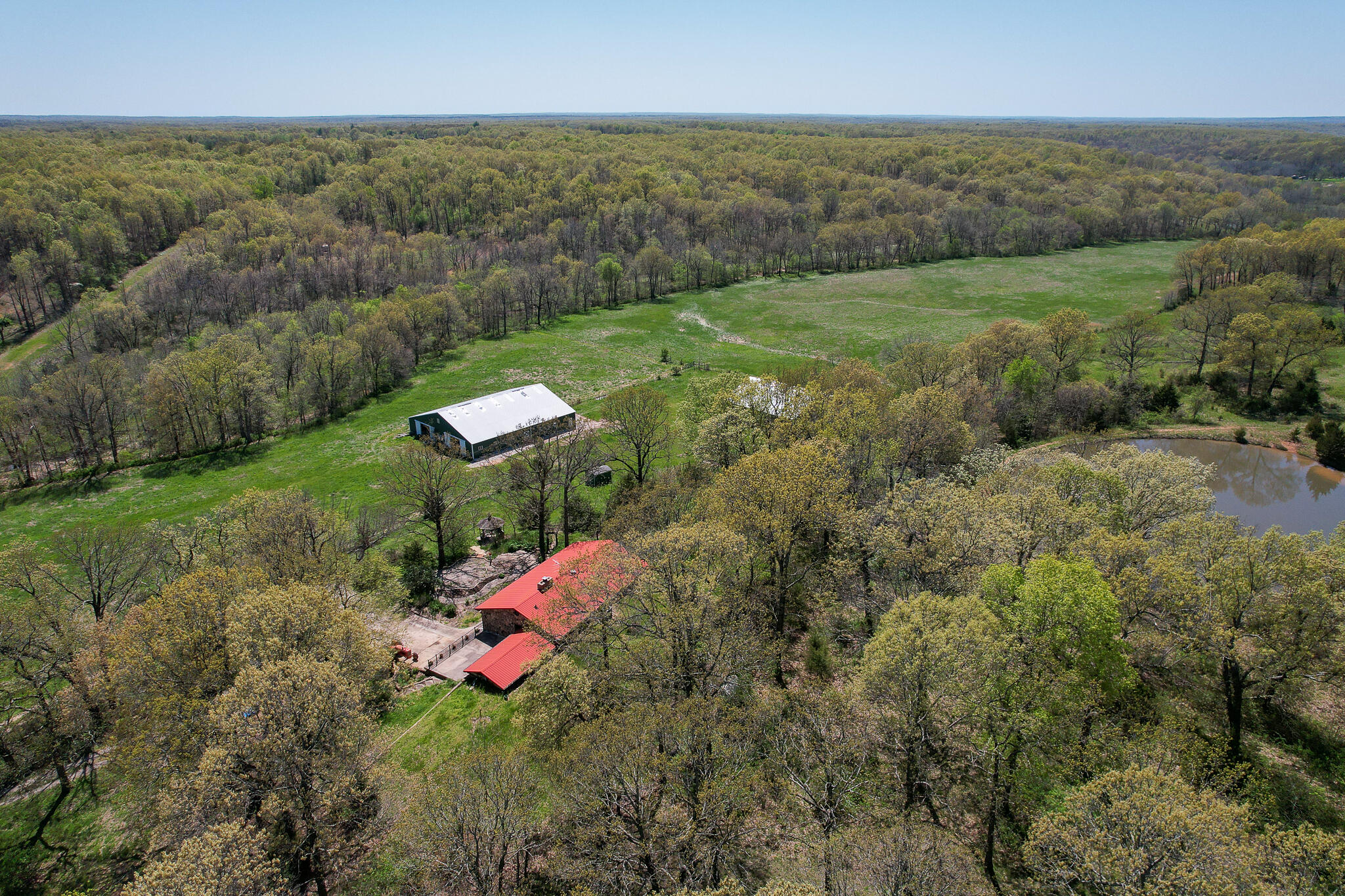 YOU WILL LOVE THIS PROPERTY!! 90+ACRES of mixed land, SPACIOUS SECLUDED HOME. A long driveway leads to this two-story charming home with four bedrooms and almost 3,500 sq ft of living space overlooking the stunning setting. THE LAND IS BEAUTIFUL, fenced, and ready for you! TWO HORSE BARNS! One is 74'x84' with 16 stalls and a tack room. The other, a 60'x60' mixed-use barn with 3-stalls, water, partial concrete flooring, and electric (both built in 1996) Also, THREE PONDS! One huge pond just behind the home that is fully stocked and has great fishing! Approx. 55 open acres producing around 60 bales of hay AND wooded land for your hunting adventures with abundant wildlife. THE HOME FEATURES TONS OF SPECIAL DETAILS, such as maple and oak floors, rustic wood trim, a study with built-in desks and bookshelves, updated kitchen cabinetry, a HUGE primary bedroom located on the main level, a newer heat pump, and lots of character all around in this solidly built home. This property is less than 10 minutes from Bennett Springs, 35 minutes from The Lake Of the Ozarks, under an hour away from Springfield airport, & just minutes from hospitals + stores! This home is a private oasis perfect for those looking to enjoy a great home on a private setting OR self-sustaining hobby farmers. Schedule your private showing today!