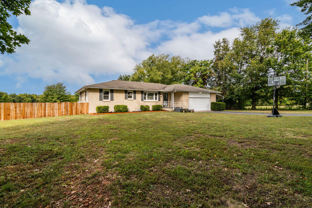 10 acres of tranquility in the Willard school district, situated conveniently close to Springfield, Willard, and Republic. This updated 3 bedroom/ 2 bath home offers 2591 square feet of living space with unique finishes. When you walk into the open living area, there is a formal dining space, a large functional kitchen with a custom wood island in the center, and a bar top area. The living room's primary focus is the built-ins of beautifully crafted reclaimed hardwood with a mantel and a cozy gas fireplace. You will find the primary bright bedroom with an en-suite updated bathroom. One more bedroom resides upstairs with two closets. Heading down to the basement, you find the third bedroom, which is oversized with a massive walk-in closet. Next door is a flex space being used as an office. And finally, the laundry room with tons of cabinets and storage space; there is also a hobby area for any of your creative desires. The basement has an exit outside to a fenced yard for your pets. The back porch is accessed through the mud room with custom built-in benches and storage. Enjoy your mornings sipping your coffee as you watch the deer and turkey enjoying the grassy landscape and seasonal pond surrounded by mature trees. InThe privacy is exceptional, being so close to the city. The property offers perimeter fencing for all 10 acres--and privacy fencing for the backyard.  There is a large workshop with power/air-conditioning and workbenches with two attached carports. Next to that is a one-car detached garage with a place for a wood-burning stove. There is an expansive, fully fenced garden area with power and water that includes six raised beds, berries, a custom-made chicken coop, and a fire pit. There is even space dedicated to a future pond. There is a pool area with landscaping and a deck. This property has so much potential for use and enjoyment. Bring your horses, sheep, goats, and cattle. Don't miss this beauty; see it today