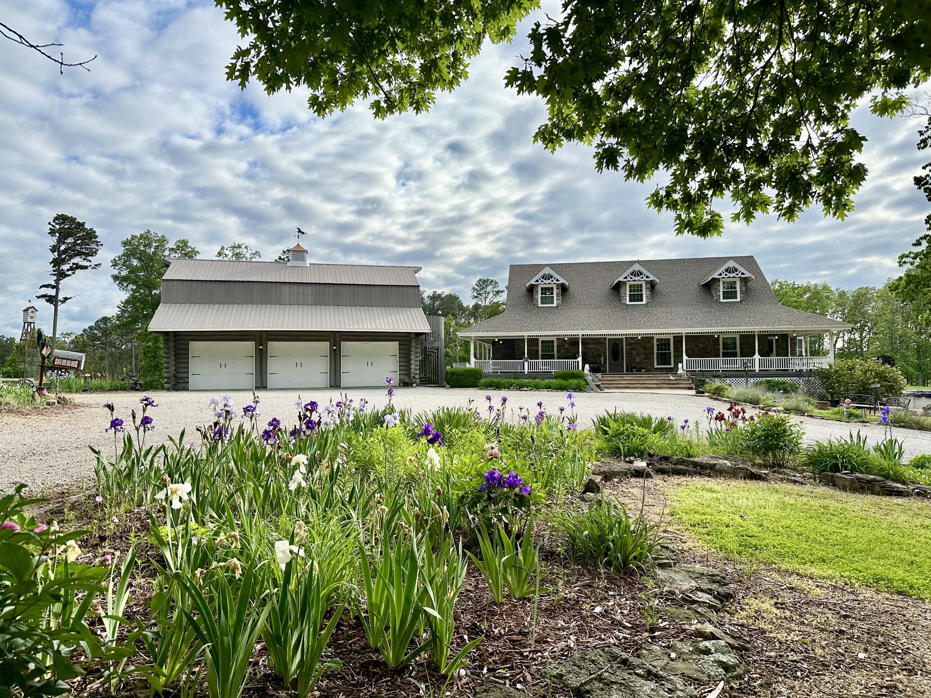 Welcome to your Ozarks oasis, a haven of serenity and luxury that beckons you to experience the epitome of country living. Nestled on a sprawling 20-acre m/l property, this custom home is a testament to craftsmanship and elegance, boasting an impressive 3947 sq ft of meticulously designed living space. As you approach, the charm of the residence is immediately evident, with a wraparound porch that invites you to take a leisurely step into the tranquility of your new home and mature landscaping. Inside the home unfolds into a spacious retreat, featuring 4 bedrooms and 3.5 bathrooms. The interior exudes warmth and character, adorned with gorgeous woodwork. The gourmet kitchen is a chefs dream which beckons culinary enthusiasts with its retro style appliances, creating an ambiance that marries functionality with style. The utility room is generously spacious and equipped with an extra oven and refrigerator, perfect for entertaining. Step outside, and you'll find a charming landscape. You'll find a pond stocked with catfish, bass, and perch. As well as a creek throughout the land. Outbuildings to include a massive 3 car garage hand built with logs harvested from the property an 1120 sq ft unfinished loft, a tool shed, and garden area.This is an incredible opportunity to own a special piece of property that has never been on the market.