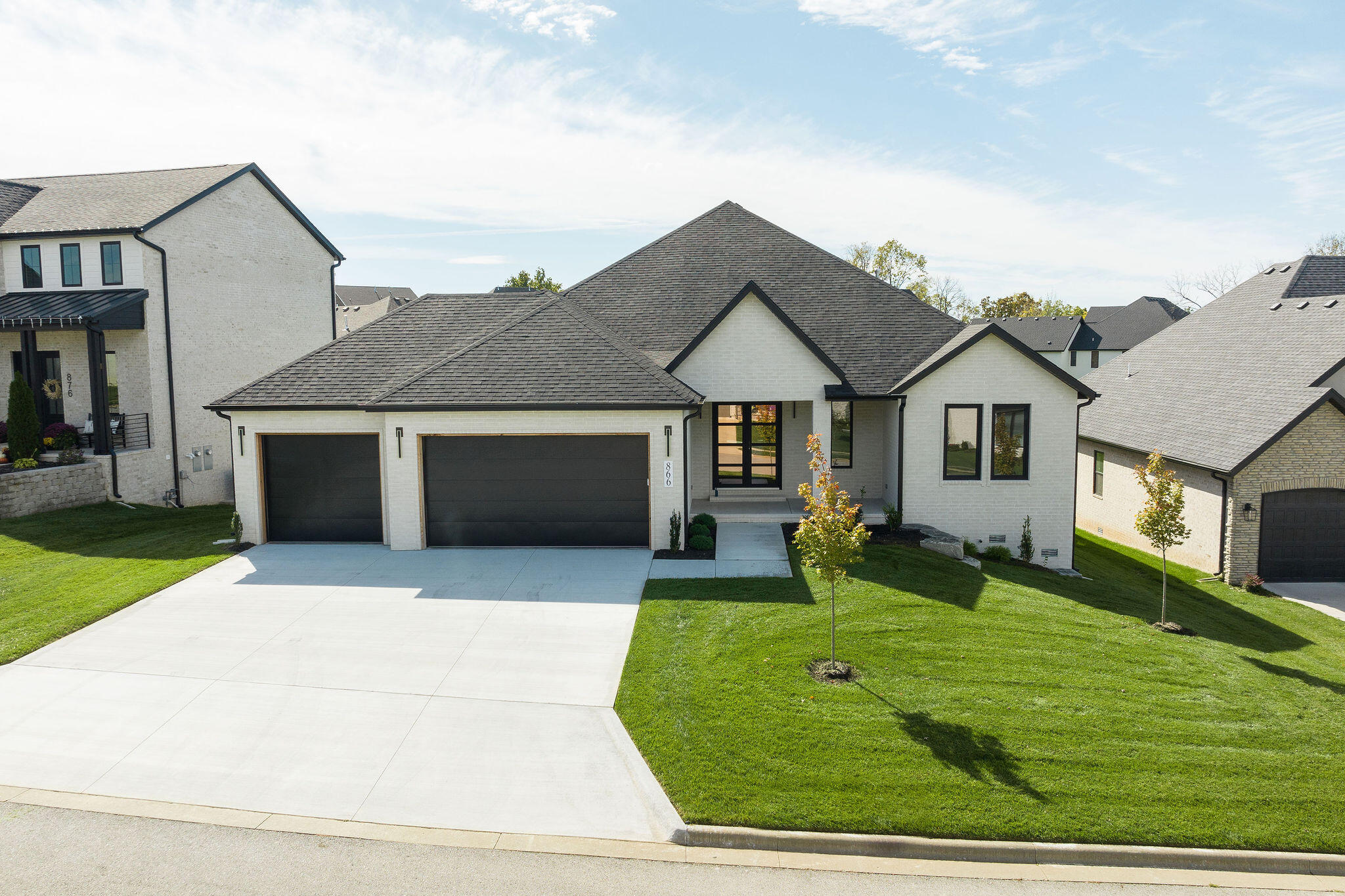 This home exudes timeless charm and modern elegance. The all-brick exterior in cream with deep brown accents creates a classic curb appeal. European-style windows add character and functionality, allowing for fresh air circulation. A spacious covered front porch leads to an inviting interior featuring American Oak acoustic slat wood wall panels, a modern light fixture, and hardwood flooring.The open layout boasts high ceilings, recessed lighting, and a clean white color palette. The living room's floor-to-ceiling black fireplace complements the sleek kitchen with all-black accents. The kitchen features white cabinets, quartz countertops, a black island with pendant lights, and high-end Samsung appliances. An expansive walk-in pantry offers extra storage.The formal dining area opens to a covered patio with composite decking and lovely views. Three main-floor bedrooms offer ample space and built-in cabinets. There are 5 well-appointed bathrooms, with modern finishes and quartz vanities. The master suite features a luxurious bath with a soaking tub, glass-enclosed shower, double vanity, and a spacious walk-in closet.The walk-out basement continues the high-end theme with hardwood floors, wainscoting walls, and French doors leading to a concrete patio and open backyard. The property is situated in Irish Hills Estate, a prestigious, family-friendly neighborhood that prioritizes preserving the natural beauty of the land. Residents can enjoy a community pool, a nearby dog park, and access to award-winning schools.