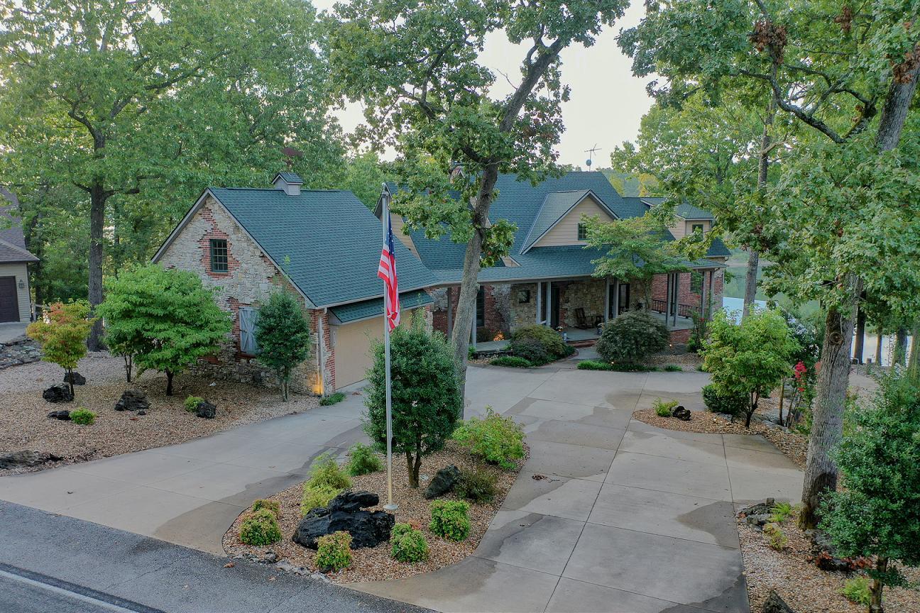 This luxurious lakefront home offers panoramic lake views throughout. Fully furnished, turn key lake home. This beautiful was once featured as 417 Magazines 'Home of the Year'. The open living, kitchen and dining area make a warm and inviting space with plenty of special touches from the professional stainless steel appliances to the vaulted wood ceilings. It offers plenty of  light from the wall of windows overlooking the sparkling waters of Table Rock Lake. The master bedroom is truly an oasis situated away from the other bedrooms and complete with its own his and her walk in closets, walk in shower, soaker tub and even a private entry to the back deck. Downstairs also features what could be considered a master bedroom with an oversized closet and entry to an attached bathroom. Huge separate living areas up stairs and down, 5 total bedrooms and flowing upper and lower decks provide ample space to entertain family and friends. The hot tub looking out to the lake is a perfect spot to relax the day away. Just below the home is the 10x28 boat slip available for additional $. All of this and access to the private community inground pool and tennis courts. Don't miss out on this gem!