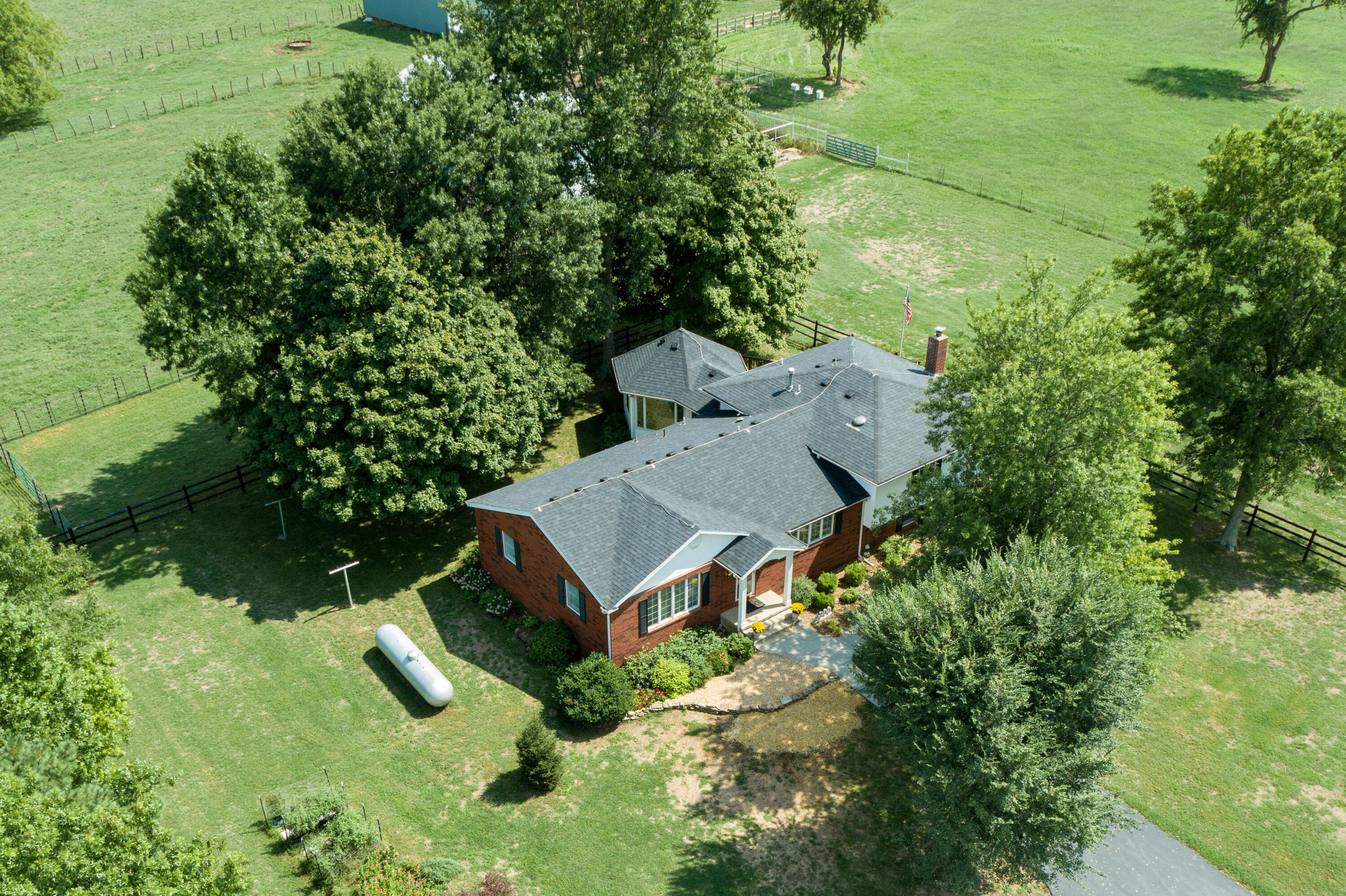 As you enter through the gated entry & wind down the private lane, get ready to be rejuvenated by the gentle nature of this beautiful countryside farm on 59.5+/- acres just West of Republic & North of Hwy 174.  The land has a gentle roll & is mostly all open with scattered mature trees. Tastefully reformed/modernized over the years is the 3 BR/3 BA home with Kitchen, Formal Dining, Living Room, Family Room & year-round Sunroom. Exterior is all brick with vinyl accents & updated windows that are mostly Andersen. Kitchen provides a Breakfast Bar, an Island, lots of cabinets & a wall-mounted TV. From the Main floor up a short flight of stairs is the Master Ste. Likewise from the Main floor down a short flight of stairs is the Family Room with free-standing Pellet Stove AND a Full Bath. The Laundry Rm is conveniently on the Main floor along with the 2 add'l Bedrooms. The beautiful glassed year-round Sunroom will surely be your favorite go-to place in the morning & at the end of a long day where you can reclaim a sense of calmness and tranquility while grilling out on the composite deck bordering the Sunroom. Tjhe 36'x40' Garage/Shop with concrete floor has automatic opener, built-in shelves & cabinets and is fully serviced with 110 and 220. The main Livestock Barn is 36'x60' with a 14' Lean-to & features automatic door openers, feeding bunks & cattle working facilities. The 2nd Barn is 45'x55', supported by steel trusses and is open to the south for hay & equipment storage. Property is completely fenced & cross-fenced for rotational grazing & hay production with numerous pipe pens. The pastures and hay fields have been very well maintained with picturesque views in all directions if a family wanted to add additional homes. The house is surrounded by beautiful landscaping, split-rail fencing & offers a partial paved driveway in front. Come see this wonderful escape from the hustle and bustle of daily life while still having close proximity to all the amenities of town.