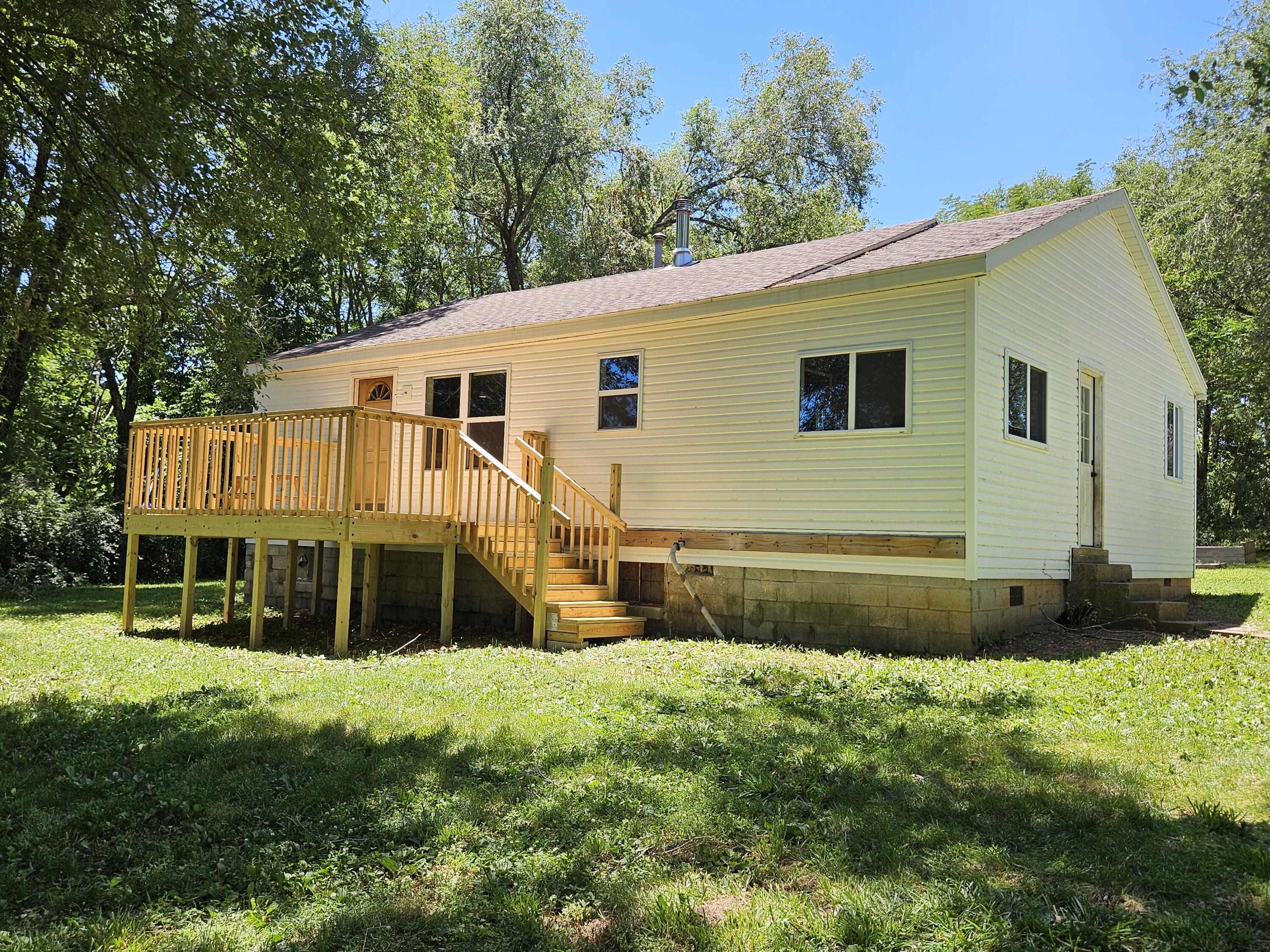 This 2 bedroom one bath farm house on 10 acres in Ash Grove is warm, comfortable and a perfect place to start a family. Property's generous size allows for multiple out buildings including a shop/garage, horse barn, and enclosed area for chickens or other farm animals or pets. Vast acrage allows plenty of room for animals to roam and children to play with much of it under the cool shade of mature trees. There's a pond on the back side of the property and lots of deer and other wildlife to observe or hunt. Garden boxes and newly planted fruit trees (4 apple and 2 peach) are both attractive and practical additions that will provide fulfillment and nourishment for years to come. Inside, home has a nicely sized living area with wood flooring, mud room at side entry, and washer/dryer hook up in basement. Master bedroom has a bonus room attached that is cleverly being used as a baby changing station/walk-in closet combo. Kitchen has farm sink, wood plank accent wall and quaint dining area overflowing with natural light. Pellet stove complements home's country character and provides exceptional warmth in the winter. Recently installed upgrades include roof (4 years old), A/C and furnace, windows, barb wire fencing for horses, and a brand new deck that overlooks the front yard. A wonderful home for new beginnings to create meaningful and everlasting memories!