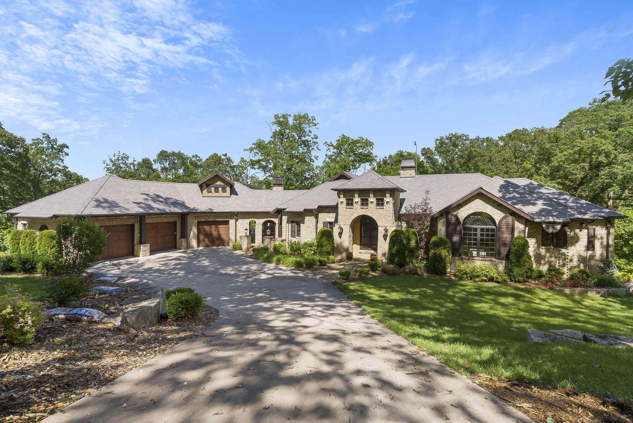 Truly one of a kind Table Rock Lake front living!! Custom built and professionally designed with exceptional quality throughout.  No expense was spared...ground source heating & cooling, 3 wood burning fireplaces,  beautiful landscaping w/irrigation system, beams used throughout home,  extraordinary cabinetry and built ins throughout, reclaimed wood flooring,  electrical and lighting package that is incredible, heated floors in master bath, gutter guards with a lifetime guarantee,  craft closet, butlers kitchen/pantry, expansive outdoor living space with a built in gas grill and mini fridge, 3 car garage, one of a kind ''finds'' that have been built in throughout the home, invisible pet fence, sound system.....do I have your attention??  When I say one of a  kind, I mean ONE OF A KIND!!  Walking in you are in complete awe...  to your left is a bookcase that secretly moves leading to a storm shelter.  Straight ahead you will see an open concept kitchen, living, and dining area.  The kitchen bar is the centerpiece as it is quite large and framed in beautiful beams.  Appliances that would make any chef happy to cook at the lake.   There is even more kitchen space, extra refrigerator, a 3rd sink and storage in the butlers pantry.  Entertaining dreams are made in this kitchen!  The great room has a cozy wood burning fireplace and a screened in patio to carry the living space outside.  To the right of the entry there is the master bedroom and bathroom w/private balcony, a half bath,  two bedrooms one of which is an en suite w/private balcony. Also, laundry room, and the cutest craft closet.  Off the kitchen is a door that leads to the lanai with an outdoor fireplace and built in gas grill and mini fridge.  Enter into the garage where there is a full bathroom and bonus room. (Bedroom #4) .  10x24 boat slip available just a buggy ride away. This is truly luxury living on the lake!!