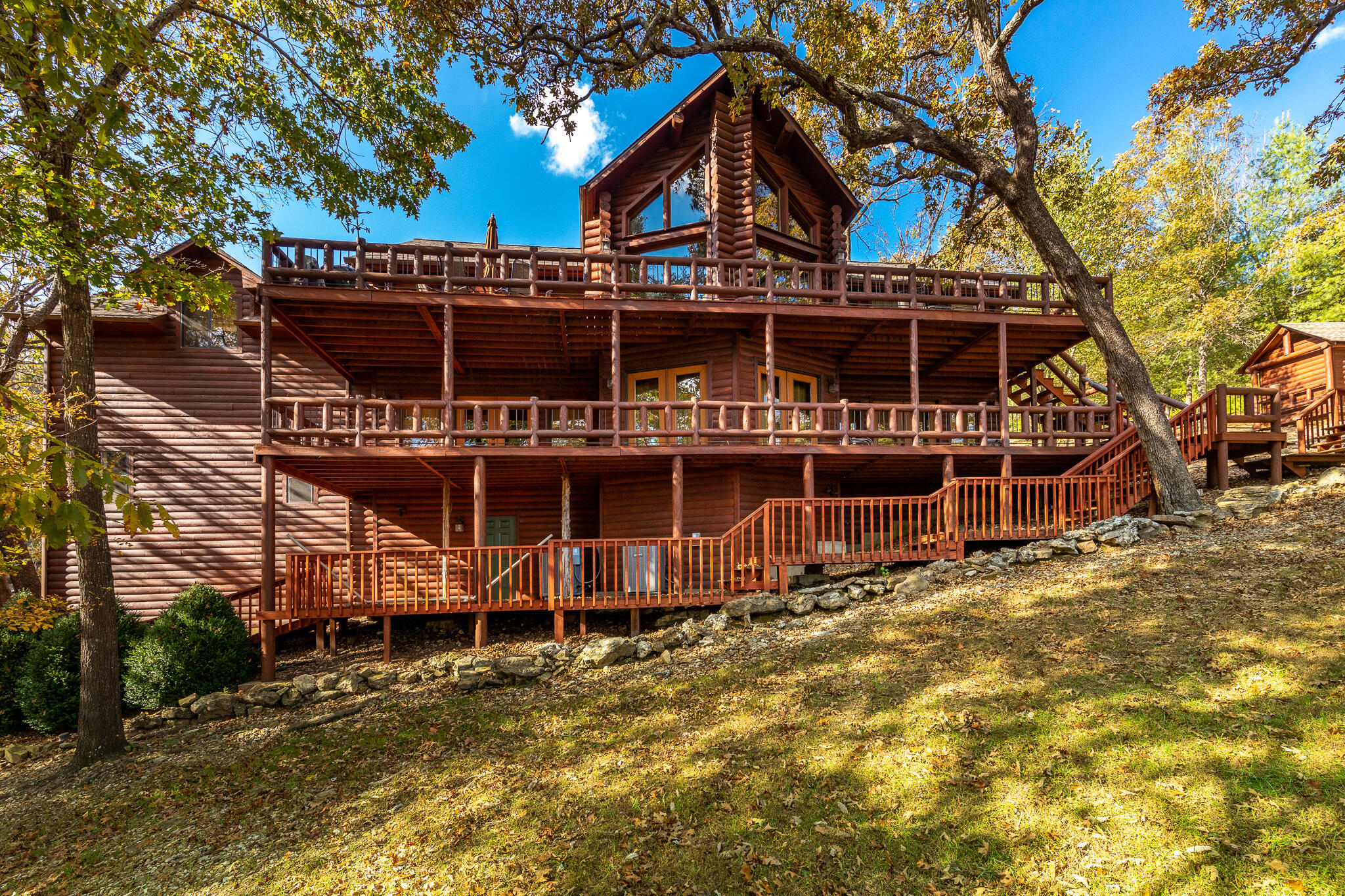 Beautiful Lakefront Log Estate with Guest Cottage and Lakeside Pavilion near Big Cedar Lodge! If you've ever dreamed of owning your own luxurious lake house, here's your chance! Outside you'll find 6.6 private and manicured acres, gated entrance, 2 waterfalls, 1 rock fountain, 60' bridge, several nature trails, an outside fire-pit, well over 200 feet of board-walk, mature timber, beautiful landscaping, large decks for patio furniture, and the occasional bald eagle! Main house features 3 bedrooms, 3 1/2 baths, 3 family rooms, large kitchen, and private dining room. The main suite has a beautiful and spacious bathroom, with stylish bathtub and large shower, plus a large connecting walk-in closet. Guest cottage has a bedroom, 1 bathroom, kitchenette, plus 3 beds in the upper loft! Sleeps 18 people! Most furniture stays please contact listing agent for details. This is truly a special property! Total square footage includes guest cabin. Seller is Owner/Agent,