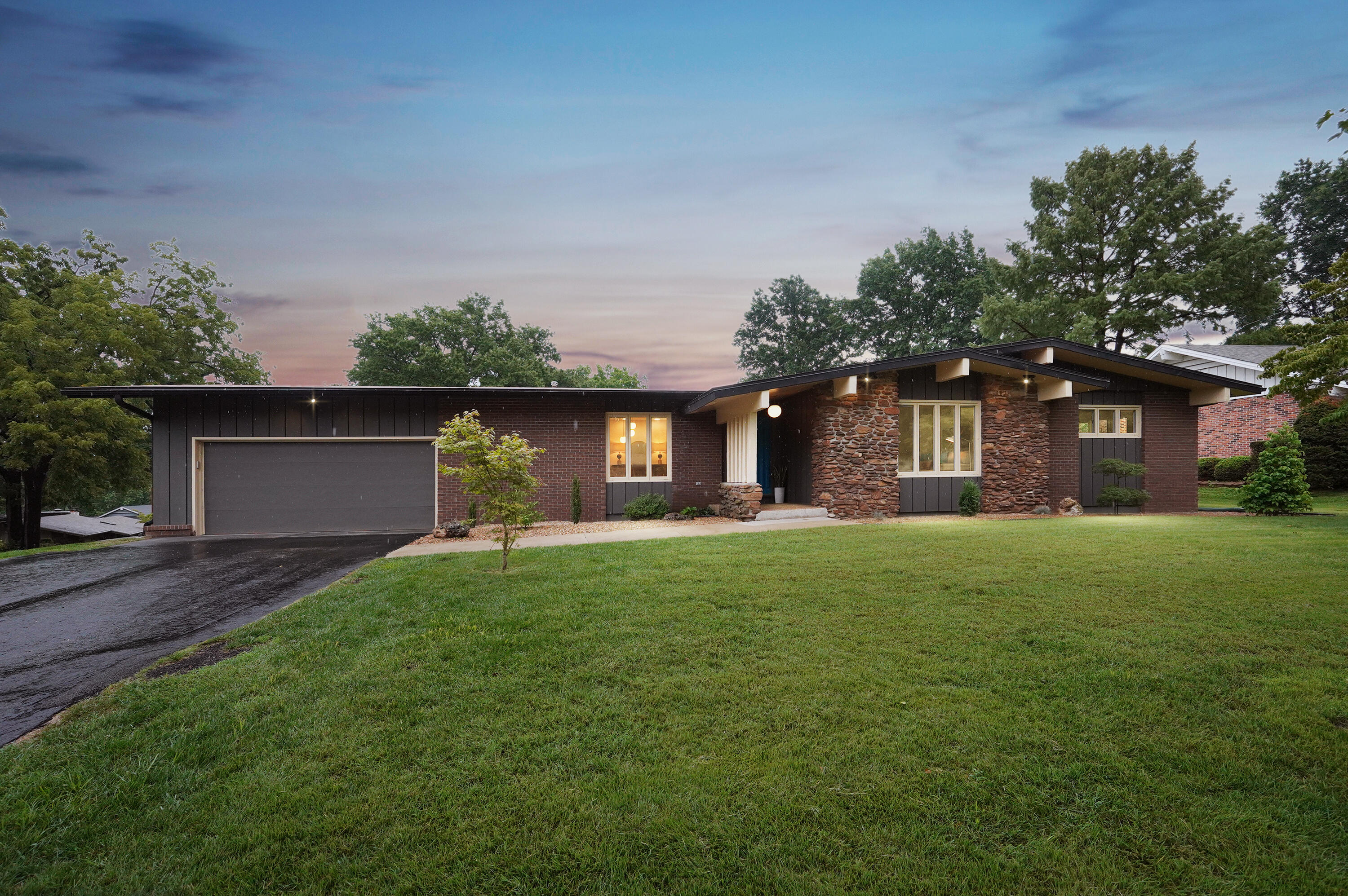 Stunning mid-century gem situated on a beautiful corner lot in a sought-after neighborhood that has been lovingly restored and updated throughout. Original character was at the center of this recent remodel, making sure to not lose what sets these mid-century modern homes apart. From the slate tile entry to the amazing wood details found at every turn, this home is truly unique and exceptional in every way. The upstairs boasts 2 large living areas with custom built-ins and large stone fireplace as well as a formal dining room with its own custom buffet. The floorplan has been opened to allow beautiful views into the new eat-in kitchen complete with waterfall quartz countertops, oversized gas stove, built-in microwave, pantry and wall cabinetry galore as well as a custom walnut stove hood and bar. The primary suite is oversized and includes beautiful custom details, new bathroom with walnut vanity, rainfall shower and brushed gold fixtures, and sliding doors leading to one of the two large patios. An extra large laundry room with work area is conveniently located by the primary suite. A half bath, mudroom, large hall bath and 2 more bedrooms complete the upstairs. In the walk-up basement you will find an oversized living space with another large rock fireplace, built-in bar with quartz counter, 2 additional bedrooms, full bath, wine cellar and additional unfinished space with ample room for another bedroom if needed as well as more living space for a media room/workout room/etc.  The gorgeous lot has an in-ground sprinkler system and beautiful plantings at every turn in the front, back and side yards. Don't miss the large workshop room inside the garage.