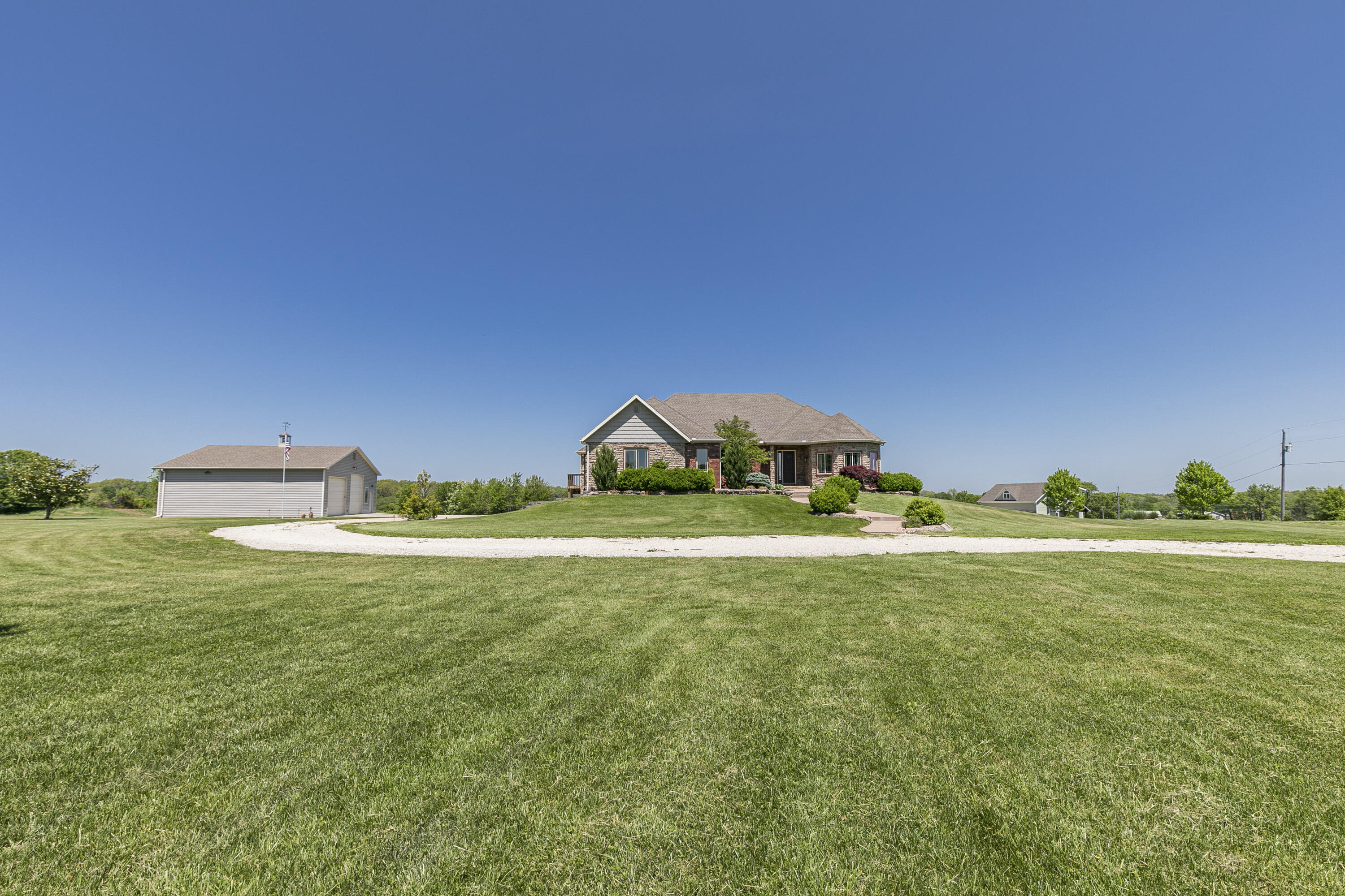 Beautiful custom built, all brick, 4 bed / 3 bath home with 4100+ finished square feet on 4.87 acres in rural Rogersville.  This meticulously maintained home sits on just under 5 acres, right outside of Rogersville, and about a 12 minute drive from the southeast side of Springfield.  As you drive up, you'll notice the wonderfully landscaped front entry complete with irrigation all around the home.  Step inside the beautiful front door, to the grand entryway with raised ceilings, opening into the living room & hearth room with double sided stone fireplace.  Continue into the large kitchen with good sized dining area, granite countertops, stainless steel appliances, huge island with extra bar seating, double wall ovens, large gas cooktop, and nice sized pantry... perfect for hosting family & friends.  Just off the kitchen, you'll find the family room / rec room with cork flooring.  On the other side of the living room/hearth room, you'll find the large master suite with oversized walk-in cultured marble shower, soaking tub, and double walk-in closets.  Also on the main level, is the unique custom office and 2nd bedroom, bathroom, & mudroom/laundry room. Head down the stairs to the walk-out basement, where you'll find 2 more bedrooms, and 3rd bathroom, along with over 2000 square feet of unfinished space, that could used as storage, or easily converted into more bedrooms or living area.  Also in the basement, you'll find the storm shelter, built-in under the front porch!  Back outside to find the large 36' x 40' detached shed / workshop with two bays.  One of the doors is over 11' tall to accommodate an RV/Camper.  Also on the property, you'll find a completely restored 21' x 32' barn, with new wood siding & metal roof, as well as cupola to match the detached shed. Other extras on this home include pella windows throughout, home generator in case of outage, central vac, & many, many other upgrades!  Call today to schedule a viewing.