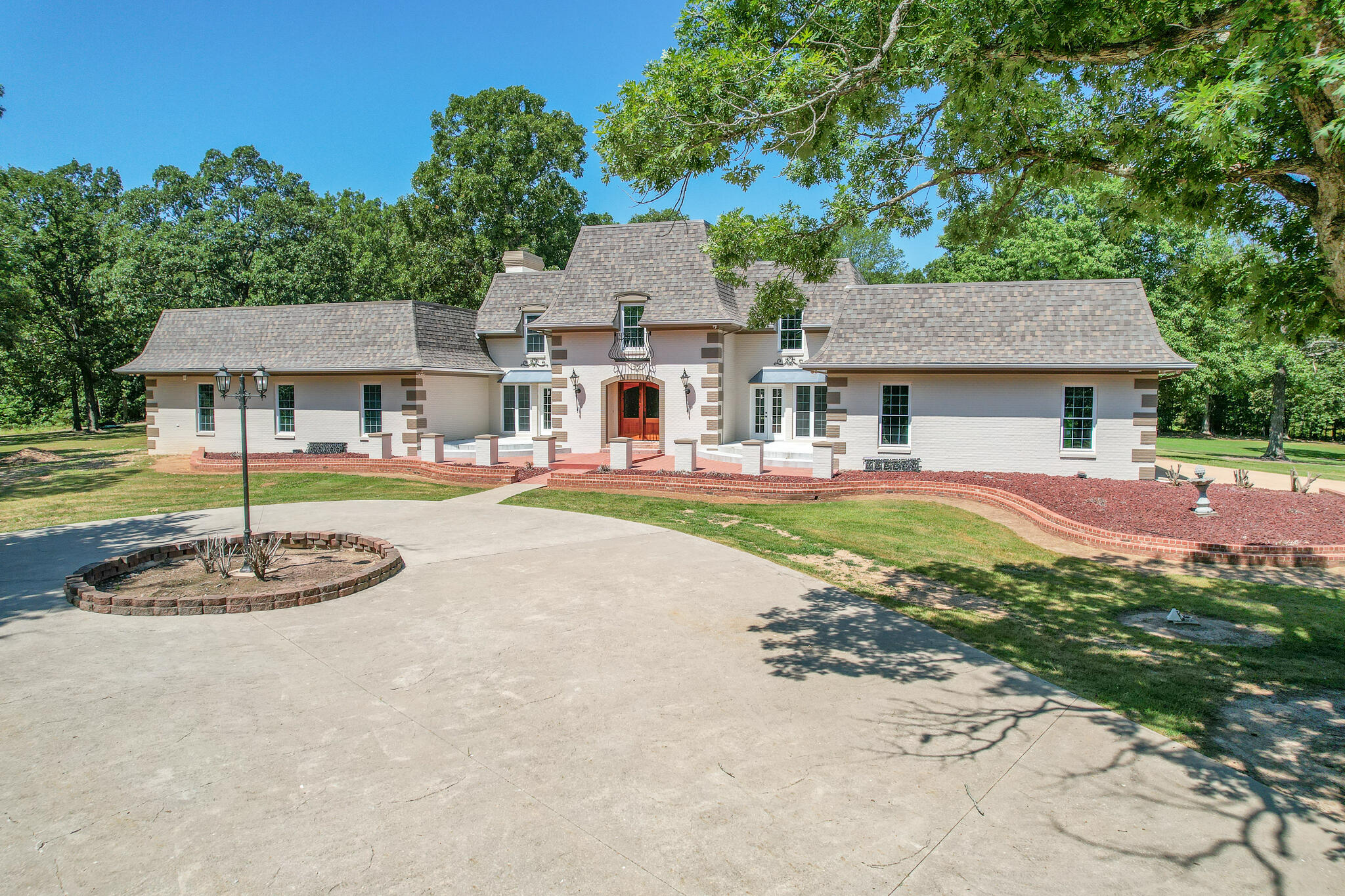 Welcome to one of Southwest Missouri's premier luxury properties. This one of a kind custom home draws you in from the minute you come through the gated entrance and down the long paved driveway winding through the large oak trees. The home features over 6,000 square feet all brick basement with 5 bedrooms, 5 full baths and 2 half baths. Custom features throughout include luxury vinyl plank floors, custom tiled entry way, large baseboard trim and crown molding. The main floor is PERFECT for entertaining large parties with an open floor concept including a kitchen designed for a chef! Beautiful neutral cabinets with gorgeous granite, Thermador propane range/oven, separate oven and microwave, Thermador refrigerator, 2 dishwashers, 2 sinks and a Hibachi grille!!! No expense was spared in a one of a kind kitchen including an enormous walk in pantry with tons of cabinets for storage and granite counters for food prep space. Adjacent to the kitchen is a good size dining area leading back to the main entryway where there is a half bath for guests. Two huge living rooms, one of which contains a wood burning firelplace along with a separate sitting room or four seasons room to enjoy the nature out back. There is a large laundry room by the garage that has upper and lower cabinets, granite counters with an oversized sink and more storage space. The master suite is a true gem large enough for any size bed and has not one, but two on suite baths. The main on suite bath has tiled floors, large soaking tub, beautiful tiled walk in shower with multiple shower heads, large vanity with granite, tons of storage, washer/dryer hookups and a large walk in closet. Don't miss the huge windows looking out back and of course the chandelier above the tub and fireplace. The second master bath has a tiled walk in shower with a glass door, single vanity, linen closet and walk in closet.