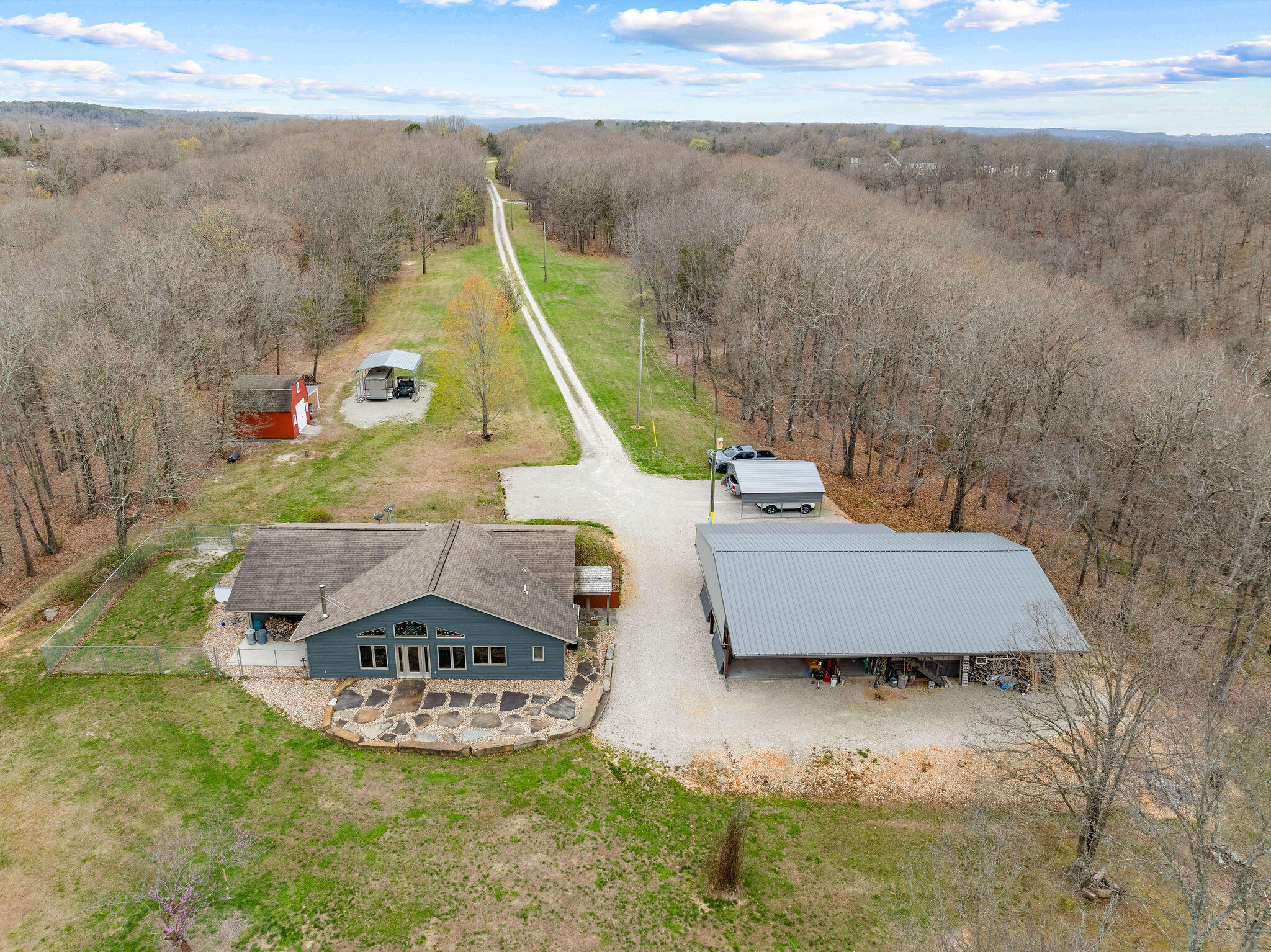 Quality, privacy and infinite possibilities await you in this home with 52.8 acres and tons of outdoor storage possibilities.  This property consists of a 3 bed/ 3 bath home with open great room with stone flooring, high-quality kitchen cabinets with two breakfast bar/island areas, dining, living area with wood stove, and entrance to fenced dog run!.  There are two primary bedrooms with full baths, an additional bedroom & a guest bath, conveniently located and a large mudroom with pantry.  Outside in the rear of this home from the great room you walk onto a stone patio, exit onto a large, fenced dog run area on right side, or exit thru mudroom to an enormous, covered patio, barn, and storage area.  The large building not only has the covered outside patio/carport area but has a large workshop, with heat and air, with double garage doors and an upstairs area for storage!  Additionally, there are two separate carports, an additional ''red barn'' storage barn with additional lean-to storage area on the right.  ATV riding trails with picnic areas overlooking wooded private property with vista views provide additional recreational opportunities.  Wildlife abounds on this property!
