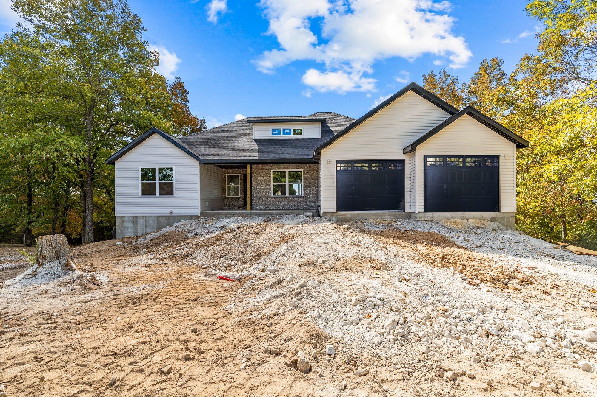 Welcome to your dream home nestled in Edgewater Village located in Cape Fair, MO! This home is under construction with an estimated completion in Mid November. Experience the ultimate blend of convenience and luxury with Table Rock Lake access just moments away. With a large living area in the main level that features an electric fireplace, this home boasts 3 main level bedrooms, 1 bedroom downstairs, and 3 full baths, this modern masterpiece offers spacious living at its finest. With the grandeur of vaulted ceilings, this home showcases panoramic views of nature at its finest from the spectacular upper and lower decks. This is an oasis you'll never tire of. The lower level also offers a generously sized finished storage area, ensuring ample room for all your belongings and more. This home also includes additional modern technology with the addition of a Programable thermostat, hard wired security cameras and an on-demand hot water heater. This home includes a generous oversized garage for all of you your toys or lawn equipment. Entertain or relax on the expansive upper deck that includes a ceiling fan and/or the lower rear deck, both perfect for enjoying the serene surroundings. The kitchen features granite countertops, plenty of cabinet space, a pantry, under cabinet lighting, brand-new appliances, including a full-sized refrigerator, ensuring every culinary need is met. But the luxury doesn't stop there. Venture downstairs to find a finished John Deere room, complete with a versatile garage door perfect for accommodating a workbench, lawn equipment or your play toys with ease. Plus, enjoy peace of mind with a one-year builder warranty included. This meticulously crafted home combines elegance and functionality seamlessly, offering the ultimate retreat in an fabulous location. Don't miss the opportunity to make this your forever home!
