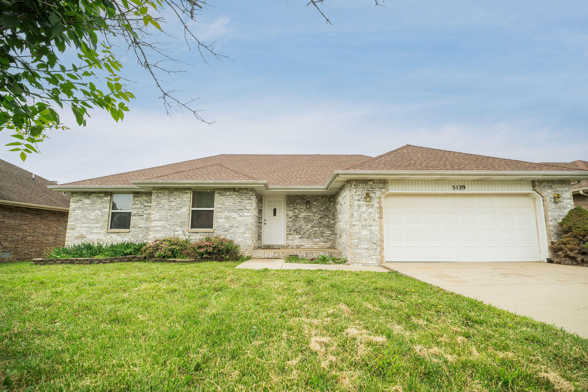 This beautiful 3-bed/2-bath all-brick ranch home with a 2-car attached garage is in a quiet neighborhood in the highly sought-after Battlefield, MO school district. Step inside the foyer to find narrow plank wood flooring sprawling throughout the home. To the left of the foyer is the formal dining room set below the trayed ceiling and a large window filtering natural light into the kitchen with matching all-black appliances and a pass-through to the living room. The living room has large windows and tall ceilings anchored by a wood-burning fireplace. The door adjacent to the living room and kitchen leads out to a spacious deck overlooking the large fenced-in backyard. With a split floorplan, bedrooms 2 and 3 are located down the hallway near the shared full bathroom, and just past the spacious laundry room with washer and dryer hookups. On the opposite wing of the house is the full master suite for added privacy with trayed ceilings, a walk-in closet, and a private full bathroom. Located just off West Bypass, enjoy a quick commute to surrounding cities while also being close to all of Springfield's city amenities including the nearby Missouri Institute of Natural Science, the expansive Wilson's Creek National Battlefield, Rivercut Golf Course, and much more. Don't miss this excellent home and call to schedule your showing today!