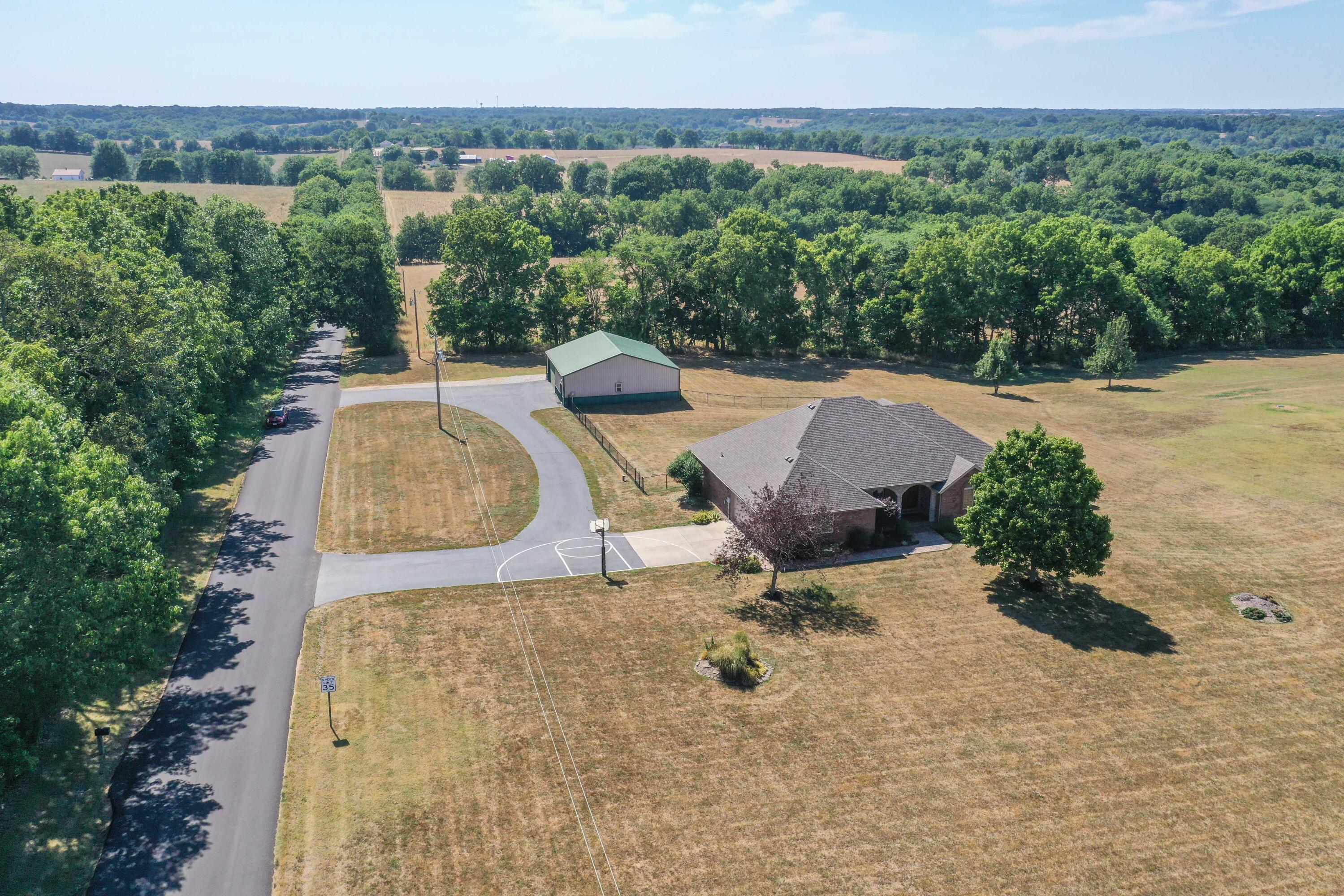 All brick and stone 4 bed, 3.5 bath home on 2.9 acres in Clever!  This luxury home features 4 total garage spaces, granite counters, crown molding, a large circular driveway, and beautiful paint throughout. Walking up to the house you will be greeted by a textured concrete sidewalk, covered front patio, and French front doors.  Inside the home is a formal dining room with tray ceiling and open arches to the living room. Kitchen features granite countertops, stainless appliances, an electric cooktop, tile backsplash, and bar seating.  Kitchen is open to a 2nd dining space, 2nd living room with a gas fireplace, and exterior access to the deck. Laundry area has extra cabinet space, a sink, and a nearby powder room.  Primary bedroom suite has stunning tray ceilings with recessed ambient lighting, his and hers sinks, and a large walk-in shower. Main floor has 2 more great sized bedrooms, and a full bathroom.  Walk-out basement features textured walls, a large family room with space for a pool table or game area, wet bar, media room, the 4th bedroom, extra storage rooms, and the 3rd full bathroom.  Outside is an oversized deck, partially covered with a built-in bench for seating and stairs down to the yard.  There is another patio area great for a hot tub, a kid's club house with electric, and a shop.  The shop is 40x40, insulated with a concrete floor, work bench, 220 power, and oversized 2 car garage door for boat storage. New roof 2019, HVAC in 2020! Asphalt resealed 7/22/22.  With quick access to Hwy 14 and James River, this is a must-see home!  Call to schedule an appointment today!