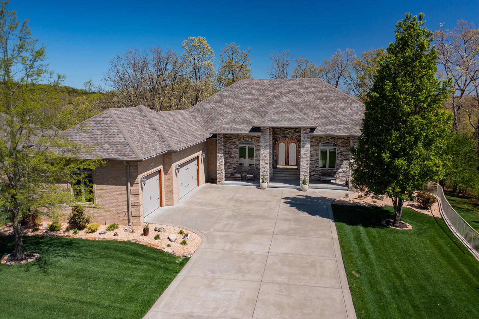 Welcome to a stunning residence in the prestigious Branson Hills community, where elegance and thoughtful design create the perfect home. The kitchen has been beautifully remodeled with freshly painted white cabinets and a contrasting two-tone island, offering a modern and sophisticated touch. The charm continues with a newly painted front door, enhancing the home's welcoming curb appeal. This home offers 4,900 square feet of finished living space, plus 1,100 square feet of unfinished space ideal for extra storage, a craft room, or a workspace. The basement includes a secure storm shelter and a convenient John Deere room with epoxy floors, perfect for storing lawnmowers and yard equipment. With direct outdoor access, the John Deere room makes yardwork organized and hassle-free. Set on a professionally landscaped half-acre lot, the timeless brick-and-stone exterior, walk-out basement, and flat backyard are perfect for entertaining or relaxing. The master suite, with dual walk-in closets, a spa tub, and a double walk-in shower, opens to an upper deck where you can enjoy serene views. Formal living and dining rooms offer spaces for elegant gatherings, while the family room with a wet bar and patio access provides casual comfort. Featuring four bedrooms, three full baths, and one half-bath, this home shines with fresh paint, wood floors, and new carpet. The three-car garage also boasts epoxy floors, complementing the durability of the John Deere room. Additional updates include two furnace/AC units, a new water softener, and ceiling fans throughout. Outdoors, a fire pit adds to the backyard's charm, while a 2019 roof and gutters ensure peace of mind. Blending luxury and practicality, this home is ready for your next chapter. Optional furniture package available--schedule your private showing today!