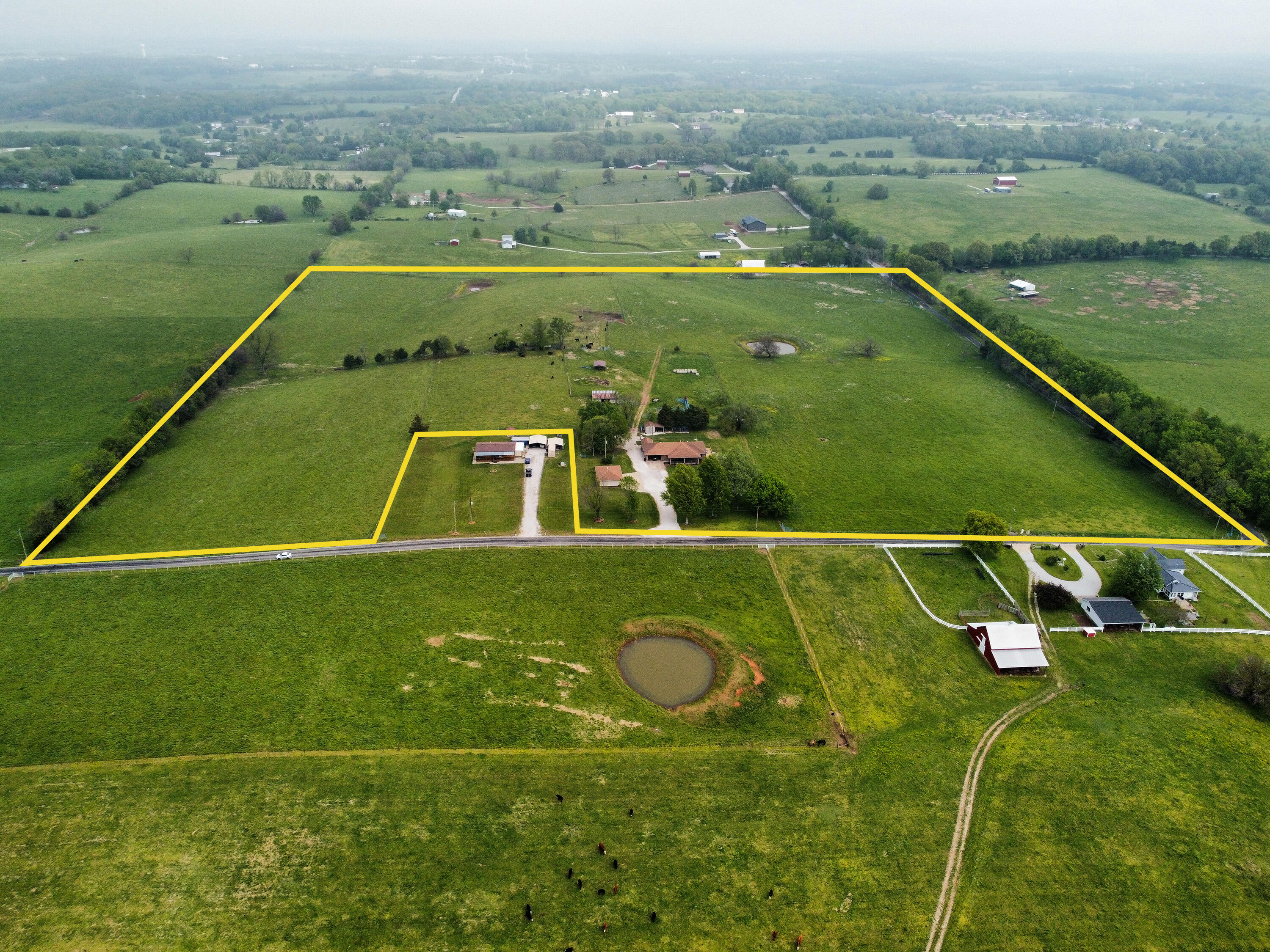 Introducing a refined, rural haven: 30 acres designed for equestrian or cattle endeavors, featuring cross-fencing, a tranquil pond, versatile barns, and three watering stations. This all-brick, two-level residence boasts 4 spacious bedrooms, a den/office, and an inviting kitchen with counter seating. The formal dining room accommodates large gatherings with ease. Outdoor living spaces include a covered porch, a spacious side deck, and a fenced backyard for canine companions. The 24x34 outbuilding presents an opportunity for a sophisticated retreat, complete with a heated half bath and ample electrical outlets. With endless possibilities, this elegant property is ideal for those seeking the tranquility of countryside living.