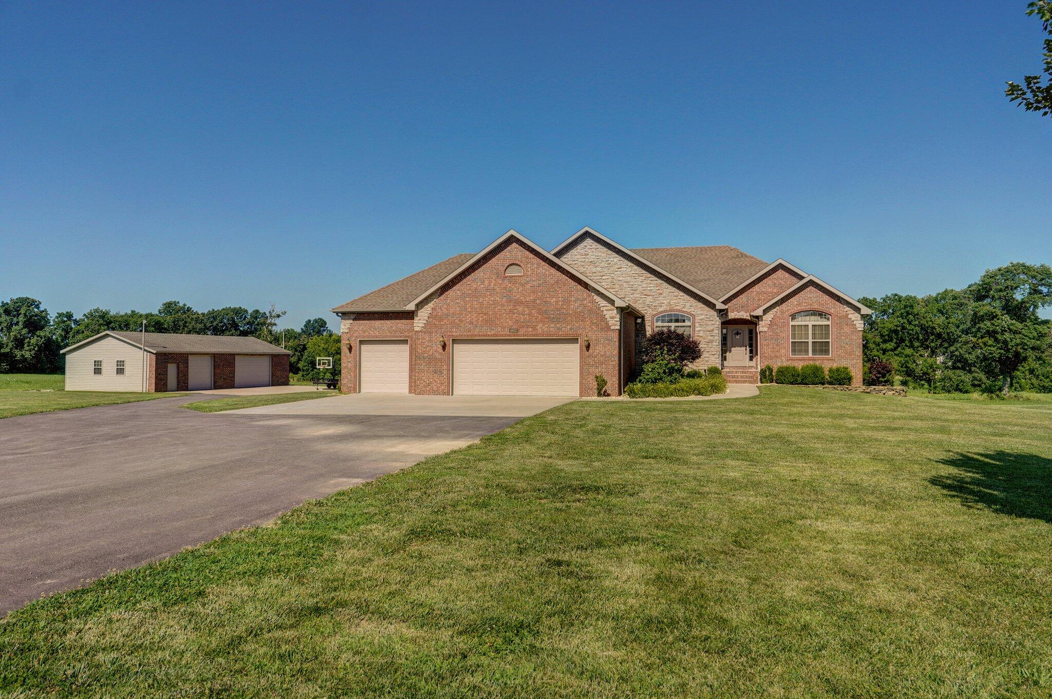 Custom, all-brick home nestled on 4 acres of picturesque land. This stunning all-brick walkout basement home offers both serenity and potential. Featuring 5 bedrooms plus an office and a nonconforming room, along with 3.5 bathrooms, it's designed for spacious living. The main level boasts an open concept layout, highlighted by a gourmet kitchen with granite countertops and LG stainless steel appliances (purchased in 2021), and a cozy living room with a fireplace and floor outlets. Step outside to a large deck, ideal for relaxing with the option to roll down screens for added comfort. The basement includes a John Deere room, ample storage, and a well-appointed wet bar with a microwave and mini fridge. The master suite is a sanctuary with its private bathroom showcasing a large walk-in closet, bath, shower, and double vanity. Each bedroom and the non-conforming room boast walk-in closets for added convenience. Additional features include a 3-car garage and a large brick and vinyl shop with a car lift, providing ample space for hobbies and storage. This property combines luxury, functionality, and the potential for expansion, offering a rare opportunity for discerning homeowners seeking space and comfort.  An additional 4 acre tract is available.