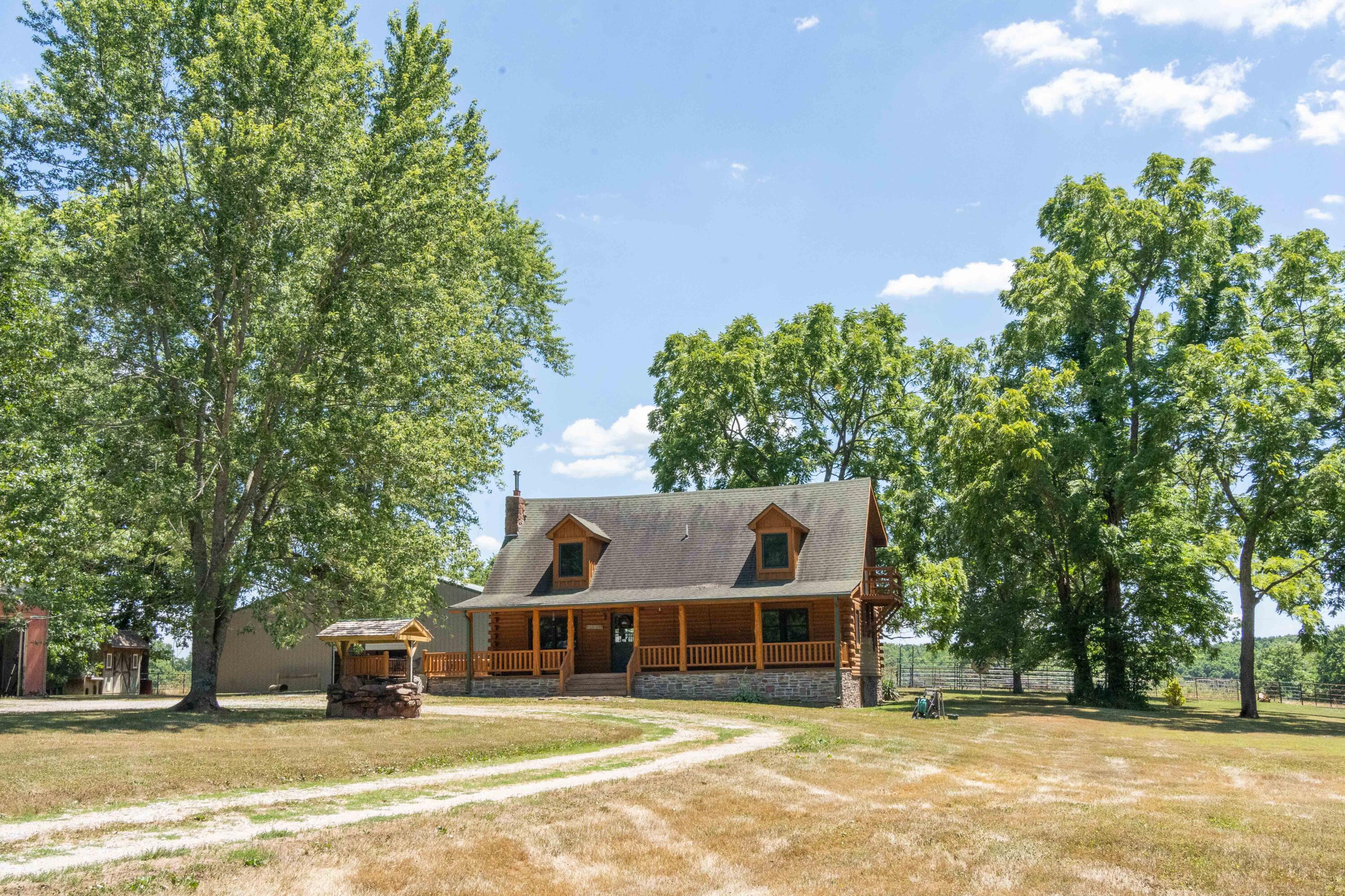 PRICE REDUCTION! This picturesque cabin sits on 34.58 acres in Rogersville, just 2.5 miles from Hwy 60. Adams Lane is about a half mile gravel road that leads up to this secluded property with a gated circle drive. The home has 3 bedrooms and 2 full baths.The 1650 sq. ft. home boasts a relaxing front porch, which wraps around to a large deck attached to the side and back of the home. It's the picture-perfect country cabin, with wooden beams and ceilings, hardwood floors, and front porch swing. The land is about 19 open acres, 15 wooded, and has about a half acre pond! It is fully fenced and operable for horses and cattle. The land is gently rolling with nice pastures and cleared wooded areas. The pond is spring fed and a great water source for wildlife & livestock. The land provides hunting opportunity for whitetail deer, turkey, and waterfowl! It is also accessible for side x sides and four-wheelers.There's a 6000 sq. ft. indoor riding arena that has plenty of lighting for use at night. The arena has garage doors on each end, a separate stall, and storage space for tack and equipment. There's an outdoor riding arena that's also lit for night use.The hay barn is 1008 sq. ft. and has 2 garage doors (one in front and a smaller one on the side for a UTV or mower). It has electricity and an elevated wooden platform to store hay. Other outbuildings include a garage to park your vehicles in and an additional small storage shed. Location is everything on this property! It's just 7 miles from the heart of Rogersville, and you still feel secluded and tucked away. The property is about a 25 minute drive to the south side of Springfield and 30-40 minutes from Ozark and Nixa. All of your necessities are close by while still getting to enjoy quiet country living. Located in Fordland School District, Webster County. Come see it for yourself!