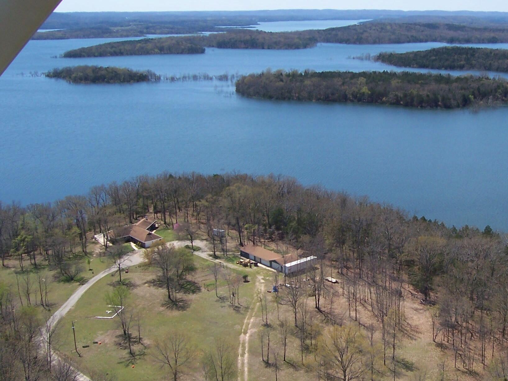 This unique, secluded lake front property has a 7-mile, Bull Shoals Lake view and you can see the far mountain tops.   The private, 3 bedroom, 2 bath home has an office/sunroom or 4th bedroom and a 3900+ sq ft patio facing the lake with a covered outdoor kitchen all located at the very end of a lake peninsula with COE on 3 sides with an easy walk to the water. The home has a lake view from almost every room and a grand native stone gas log fireplace in the living room. The recently updated kitchen has stainless steel appliances and butcher block and new counter tops. All appliances included and owner is providing a home warranty. The 5.33 acres, m/l, property is at the end of the road, gated and could be a prepper's haven, just add solar.  Also, on the grounds is a 24ft x 84ft insulated shop building with 6 bays, office area and a bathroom with shower.  There is a 12ft x 60ft greenhouse/high tunnel with raised beds for almost year-round vegetables and a lighted helicopter pad, high speed fiber optic internet and great hunting.  Included is a boat stall with a lift in a covered dock, solar power, locker, swim platform and ladder. And, so many more features.  Must see to believe the view.