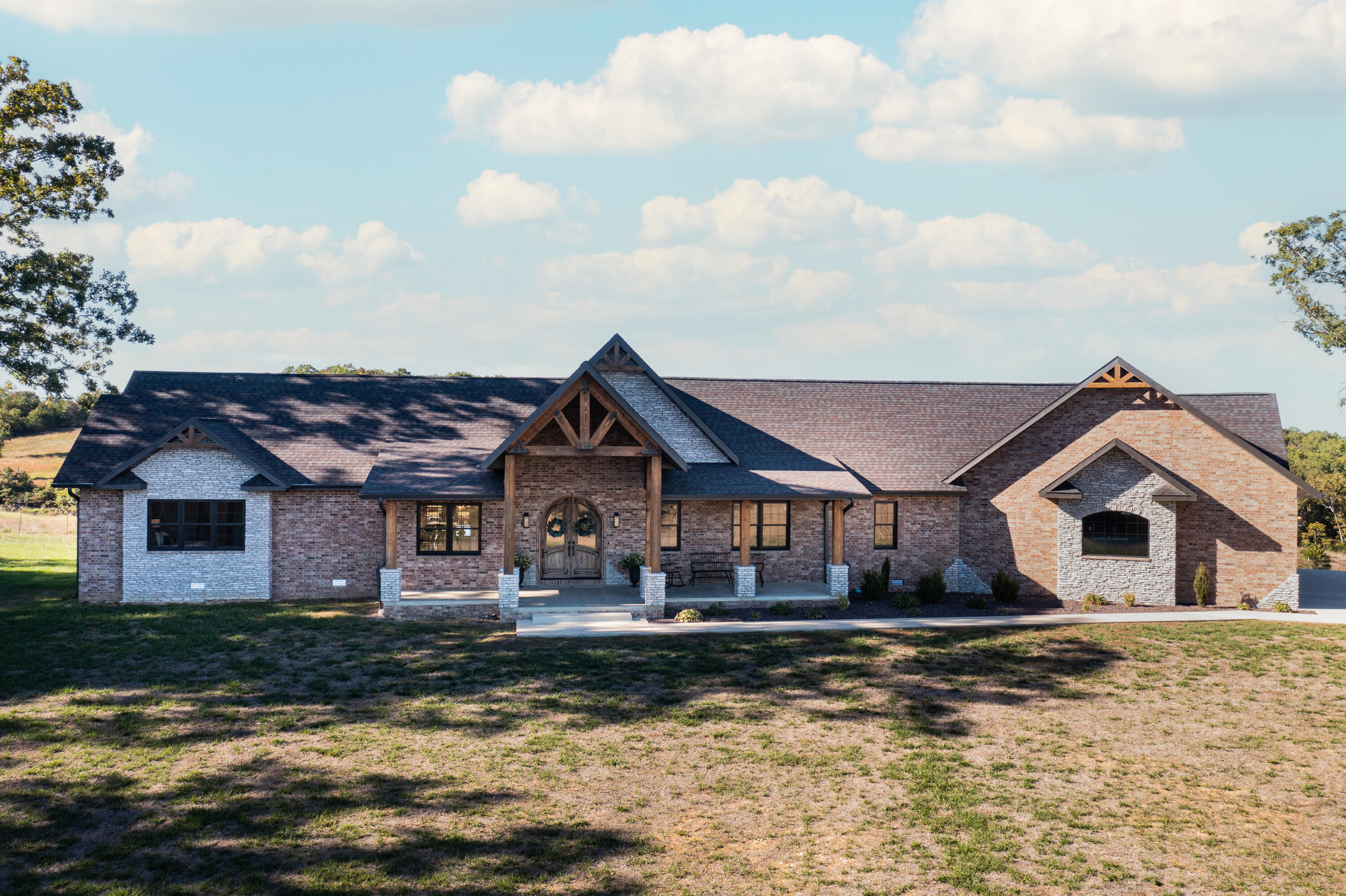 Secluded Custom Brick Home with stone accents and timbers throughout! 4 Bedrooms, 4 full bathrooms, and 2 half bathrooms - Custom cabinets with granite counter tops in the kitchen, bathrooms, and laundry room - Walk in Pantry - walk in closets for each bedroom - gorgeous stone fireplace going 22 ft up - massive hand constructed timbers - custom hardwood floors and tile work - home is built with a 12/12 pitch for large vaulted living room and master suite - stainless steel appliances in spacious upgraded kitchen with large island - floating concrete back porch - finished partial basement offering gun vault room with vault door, full bath, John Deere room, storage, additional living room and electrical/mechanical room.  HVAC is state of the art GEOTHERMAL system with parts and labor warranty - Home sits on 153 acres with 2 small barns - state of the art cattle working facilities - catch pens with waterers - spring fed pond - other smaller ponds - huge deer stand in the middle of cut out food plot with shooting lanes.  Many large deer and turkeys are harvested off this farm each year.  Entire property is perimeter fenced, with piped corners, and large piped entryway - cross fenced and woods are fenced out - all put in recently.  Property does offer marketable timber in the wooded area.  Rare Opportunity!  Don't miss out on this stunning property!