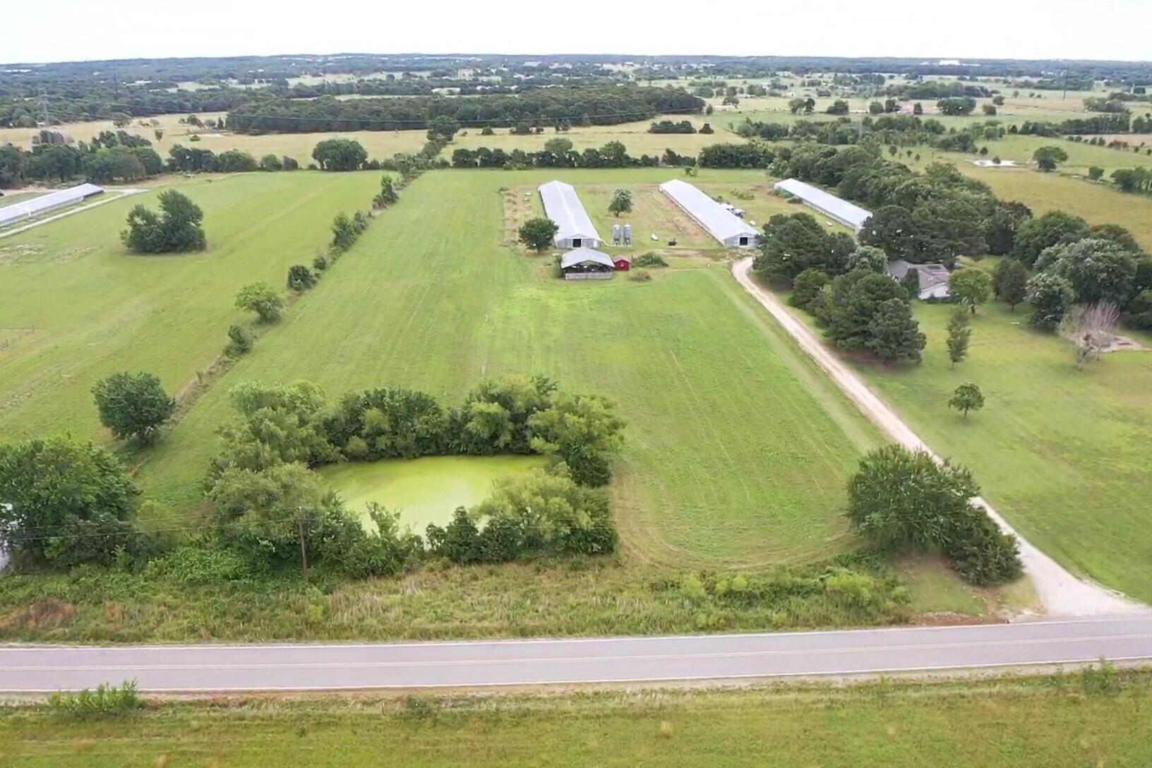 NWA is a great place to live in America and people keep moving in and we are growing. Buildable land is in demand and this is a fine 10 acres to call your own. Drive down peaceful and paved Bloomfield and see farms and fields and homes, then turn in to your own lane and home, where you've come to know your neighbors. Cast a line in your own pond or have your local farmer cut hay off a part of your 10 acres. Mostly open and level and containing one retired dirt floor chicken house (40'x400') you'll be on septic (once approved) and your choice of public water or well water. Dimensions in the aerial view are approximate and subject to a new survey. Come have a look!