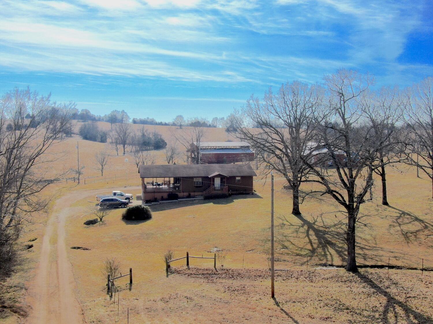 To View All Listings in The Ozarks Click Here. Gorgeous views, wildlife and the fruit of your own farm are sure to abound on this 50 m/l acre farm in the rolling Ozark hills of south central Missouri. Farm is over 90% open with a lot of grass for grazing cattle or other livestock. Property is fenced with some cross fencing. The south end of the farm also has a spring that the seller has never seen run dry! The property has 5 ponds for watering livestock and an automatic water tank in the working lens close to the house. The house is a very well maintained 3 bed, 2 bath home with two living areas, spacious upstairs covered deck and a 2 car carport attached to the basement. If you need more beds you could easily enclose the downstairs workshop/garage area or the deck upstairs and have anywhere from 5-7 bedrooms! The farm also comes with an RV hookup, additional septic system that was used for a mobile home, a dairy barn that could be reused or converted into storage, a 40x60 hay barn and a lighted riding arena that is approx. 97x240! If a farm just 15 mins from town, in the beautiful Ozark hills is what you're looking for, don't delay! Farms like this don't come up very often.