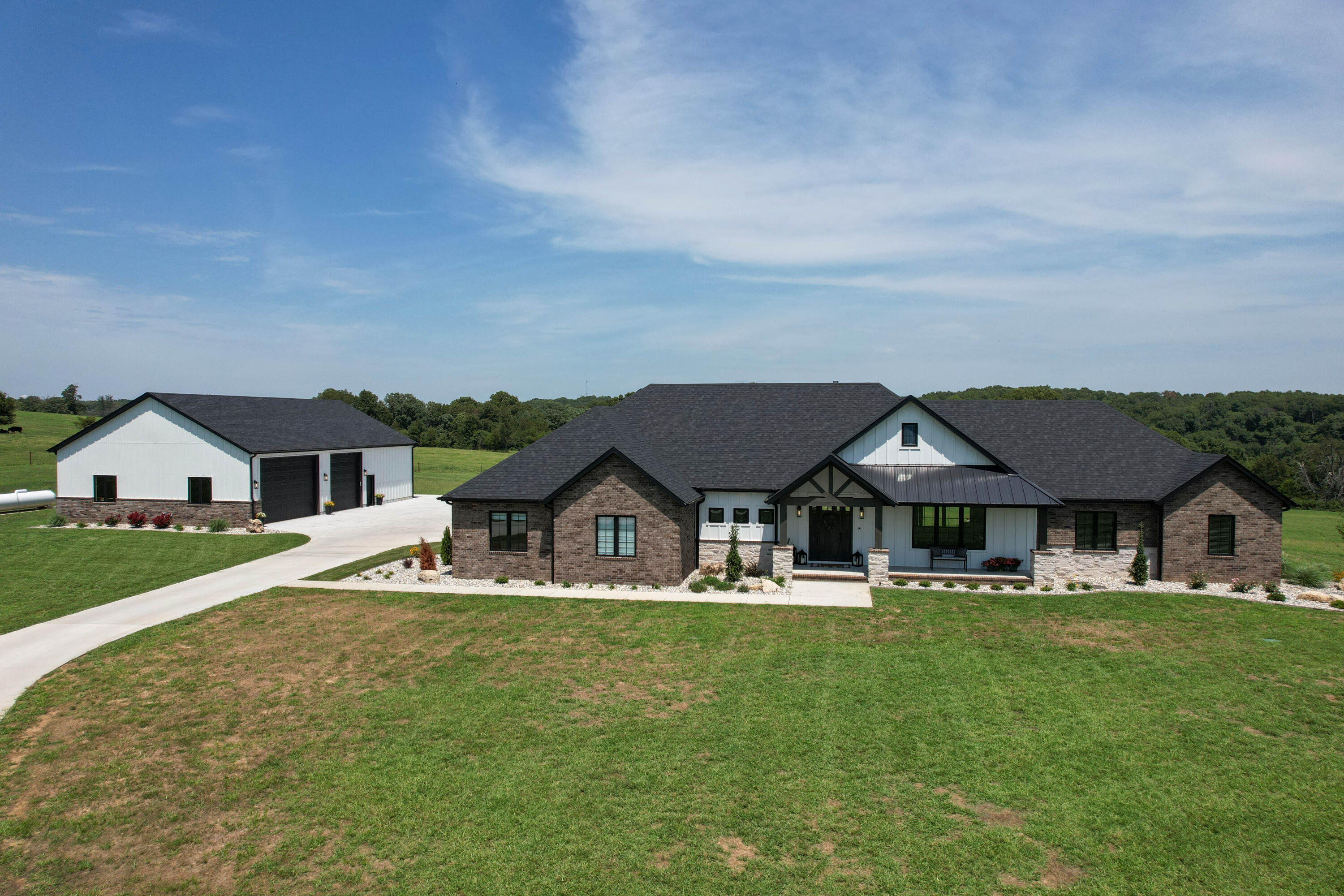 Look no more! Gorgeous custom home and shop on 5 acres m/l. This extraordinary home is all on one level. Property is open and embraced with beautiful country views. You will not want to leave!  Exceptional hardwood floors throughout, custom tile and extra large closets. Family and friends will gather in the spacious kitchen with a large island. Includes double ovens, gas cooktop, huge walk in pantry w/ coffee bar and plenty of windows. Upgraded gas fireplace pulls in the charm.  Primary suite is sure to please with a large soaker tub, walk in tiled shower, and an extra extra large closet with built in dressers to keep everything organized!  Property is wired for security, generator, surround sound in living room, kitchen and back patio.  AT&T fiber internet and WiFi net distribution system in house and shop. Irrigation system.  Oversized 3 car garage with a walk in storm shelter. 5+ garage total with shop. House has two high efficiency HVAC units, ERV system (energy recovery ventilation), foam insulation. Crawlspace is conditioned and foam insulated as well.  Inviting covered front porch and covered extra large back patio that extends beyond for relaxing and entertaining.  Expansive concrete continues from house to shop. Beautiful setting! 40'X 60' Shop includes full bath w/shower and washer and dryer hookup. Wired for TV, internet and in wall speakers.  12'X18' garage door, 12'X12'' garage door, high efficiency HVAC and tankless water heater (in house and shop), foam insulated walls and ceiling, and finished drywall on walls. 1000gal propane tank owned.  Exterior of shop matches house.  Property also has its own private well.  Fantastic location south of Nixa in Daybrake Ridge Estates!  WOW!