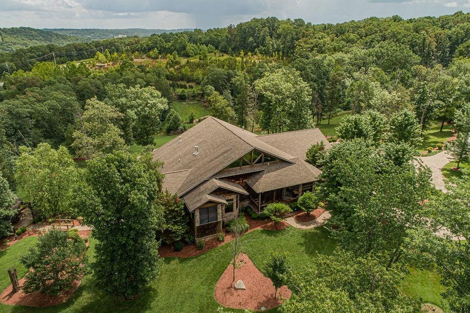 One of a kind private retreat situated on just over 18 acres with 3 separate living quarters that are being sold turn-key furnished less a few personal pieces. The 3168 square foot main level offers plenty of room for entertaining with a large open floor plan. Warm wood accents including hand-scraped hardwood floors and tongue and groove ceilings throughout are complemented by the wall of windows overlooking the beautiful back yard and scenic lighted pond with fountain. Ornate wood and stone surround the Living Room Fireplace with the true Chefs Kitchen, Formal Dining Room, cozy Breakfast Nook and screened in porch completing the living area. The Split-bedroom layout features an En-Suite with tiled walk-in shower on one side and the Master Suite on the other. The Master Suite offers a sitting/study area with fireplace, and the luxurious Master Bath features heated tile floors, dual sinks, a separate vanity counter, fireplace, whirlpool tub and walk-in tile shower. The partially covered back deck is the perfect spot to relax and enjoy the views of the pond. The separate 1370 s/f lower level is also an open layout with split bedrooms, each with their own full bath. The living area is open to the full kitchen and dining and features a beautiful Gas Log Fireplace with a wall of windows looking out onto the back yard and pond. The large patio offers both covered and uncovered areas perfect for great outdoor entertaining as well as relaxing. A quick stroll across the Stream Bridge brings you to the Cabin, loaded with warmth and charm. Complete with a Full Kitchen and Living area with Stacked Stone Fireplace, relaxation is assured. The private bedroom and full bath complete the inside, and the wrap-around deck makes the perfect spot to enjoy morning coffee or a relaxing end of the day spot. Located in the heart of Branson and also approved for 67 Nightly Rental cabins plus multiple additional structures, this is a Must See!
