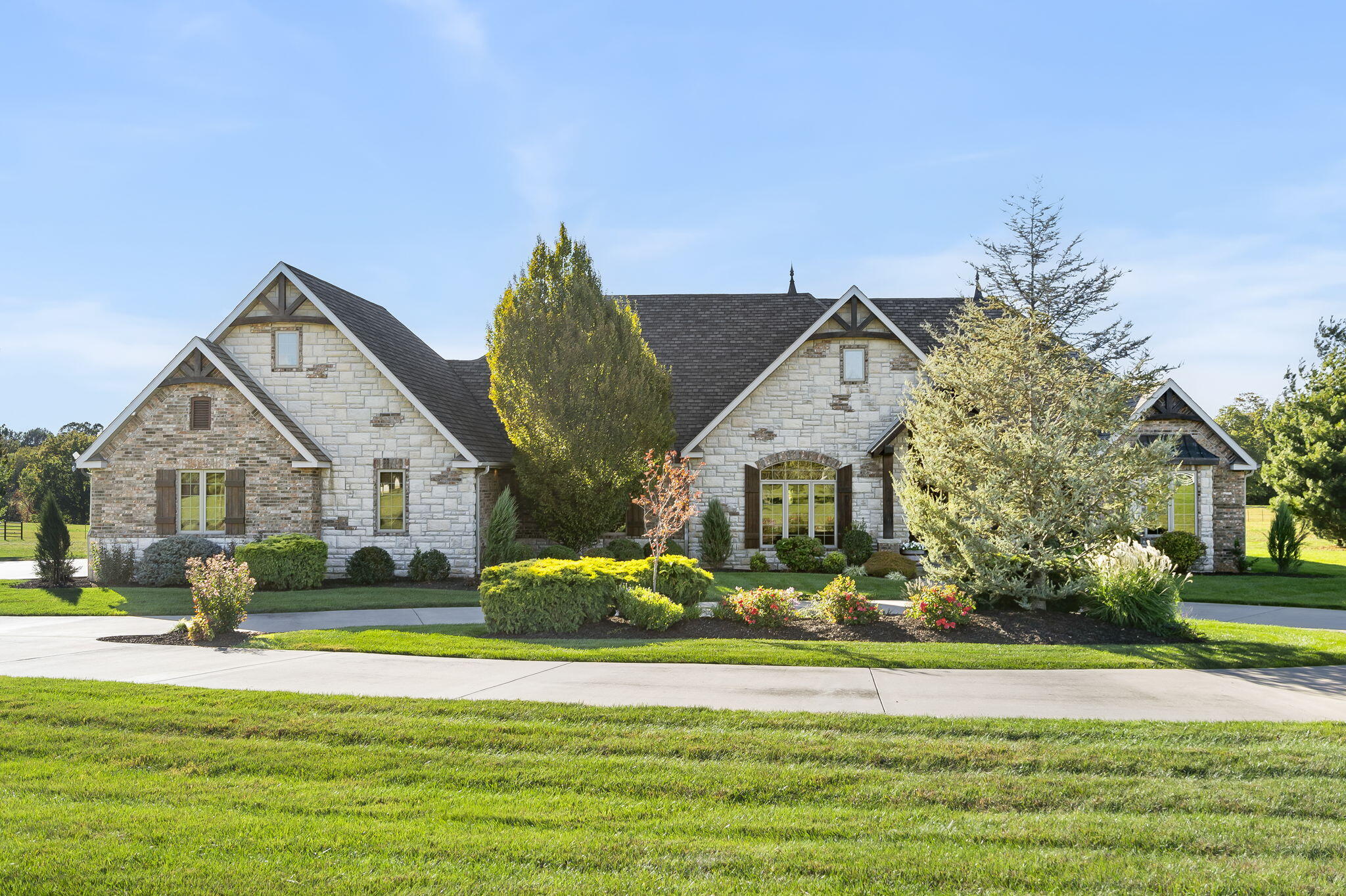 Rustic Elegance in East Springfield, Strafford schools. Options of purchasing the main home with 5, 10, or 20 acres. If purchasing all 20 acres there is an additional 2 bed, 1.5 bath, home with approx 1312sqft, plus a 3 stall barn, detached tack room, and 2 detached garages/storage buildings. Main home is all brick & stone exterior with stunning wood beam accents inside & out. High ceilings, 8' solid Alder doors, large lodge-style windows, hardwood flooring, energy efficient & low maintenance design. All living on one-level, featuring a great room, formal dining room, open layout concept kitchen, eat-in kitchen area, and a large all-season room with incredible views. There is a split bedroom floor plan with 2 bedrooms and a jack-and-jill bathroom on one side of the home, and the primary suite and 4th bedroom on the other side- split from each other to the front and back of home for privacy. The primary bathroom connects to the huge walk-in closet which conveniently connects to the laundry room. An office and 3rd full bathroom complete the main level. The unfinished walk-out basement has approx 1200sf, and features a concrete storm shelter, easy access to mechanical components, and access to the insulated, heated & cooled crawlspace. Main home also features an over-sized 3 car garage w/shop area, and covered flagstone patios -in front and back, to enjoy the breathtaking sunrises and sunsets! Large covered back patio has a fireplace, pull-down shades and plenty of space to grill and enjoy the panoramic views. Land is cross-fenced and has livestock waterers. Concrete lane leading to the property with circular driveway. Gorgeous landscaping, and an overall meticulously maintained home. Great location off Hwy 125 between Chestnut and Division, quick access to I-44, Hwy 65 & Hwy 60.