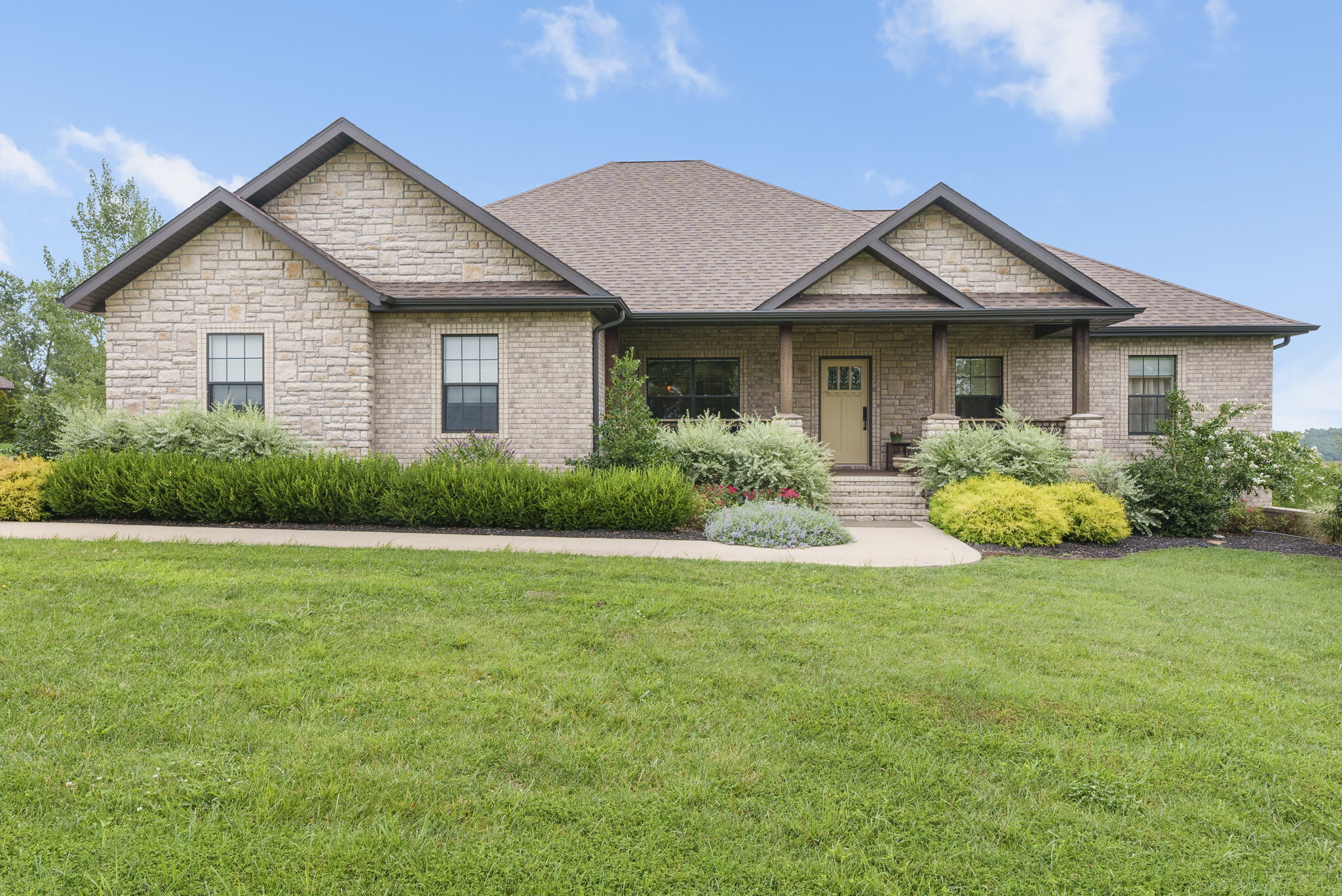 This must see, stunning craftsman style home with all brick and stone exterior is beautifully landscaped, including high quality sprinkler system, offers breathtaking views of the rolling Ozark hills from every room!   Your first step inside will wow you with the custom woodwork and cabinets throughout including the custom wood floors and porcelain tile in the bathrooms.  Details continue with classy pocket doors, gorgeous kitchen of quartz/travertine w/ high end appliances, custom window treatments throughout, and spacious closets.  No feature was missed including state of the art electrical with int/ext ceiling and low lighting, water softeners and filtration systems.  You'll be amazed with the storage in the John Deere room and then step outside to experience the Trek decking and stone floor on the exterior to enjoy the view!