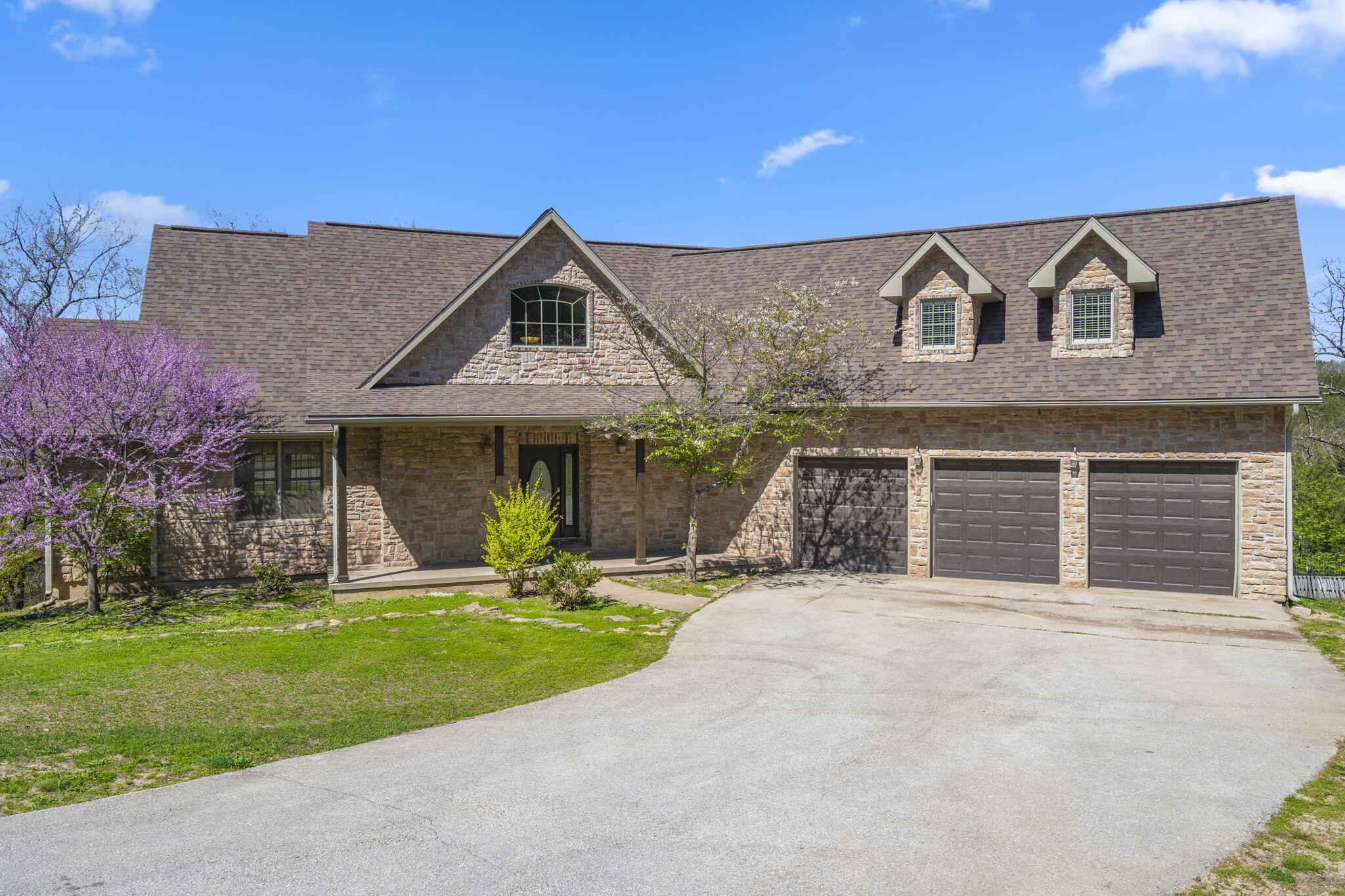 Sitting in a gated neighborhood, just outside of the Branson city limits on 5 acres is 155 N. Sycamore Falls Trail. This beautiful home is being offered with 10.97 acres for $670,000 or with just 5 acres for $630,000. The HVAC system was replaced in 2022 and the roof is only about 4.5 years old. On the main floor you will find everything you need from a large primary bedroom suite, kitchen, living and dining areas, a guest bathroom and even the laundry room. The upstairs has three more bedrooms (one is the large room above the garage) and another full bathroom. The basement offers another living space, a full bathroom and two more bedrooms (one is unfinished). You are sure to enjoy sitting on one of the two covered back decks and enjoying the wooded view. Don't forget to take the virtual tour that is attached to this listing and call your REALTOR(r) for a private viewing today!