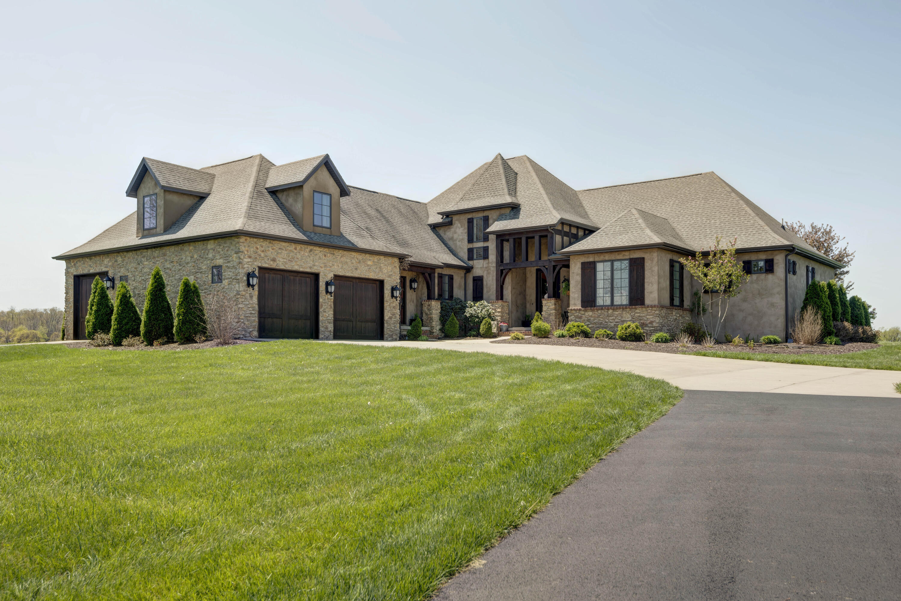 STUNNING CUSTOM BUILT FRENCH COUNTRY HOME WITH 36+ ACRES LOCATED IN ROGERSVILLE SCHOOL DISTRICT!  You'll know this home is special when you drive up the private drive with the panoramic views to the magnificent setting.  This timeless home boasts of warm wood floors, heavy beams and beautiful stone fireplaces.  The large kitchen features an island, gas 5 burner stove top with a pot filler, Bosch double ovens and dishwasher.  The kitchen flows into a cozy hearth room.  It also has a large walk in pantry.  The utility room is loaded with storage and space to make your laundry days better!  The master suite and bath is extra special and you'll love the large walk in shower and the walk in closet is also a storm shelter.  The main level includes 3 bedrooms and 2 1/2 baths.  Upstairs has another living area and 2nd master suite plus a huge walk in attic storage room.  Four bedrooms have their own private baths plus walk in closets.  You'll also love the outdoor space with a large covered patio and additional patio space to enjoy the views and outdoors.  The land is mostly pasture, some timber and 5 acres for high value horticultural crops.  Two acres have been cleared of rocks.  They have grown sweet corn, water melon, pumpkins, squash and drip irrigation culture strawberries. All this plus a pond and a 20X30 3-sided barn.  This home was quality built by Brian Powell.  This is your chance of a lifetime to own a country estate!