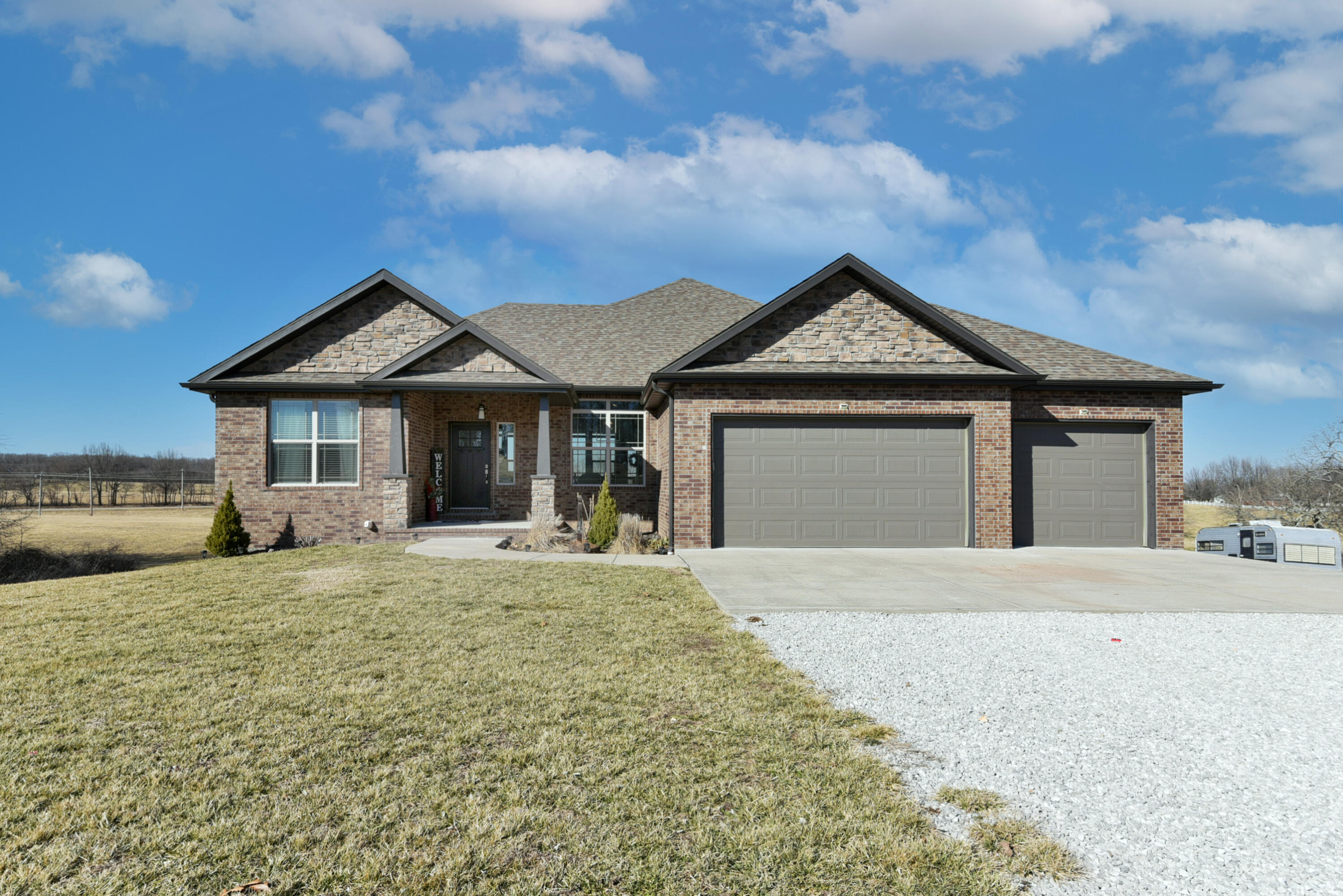 This modern 6 bedroom 3 bathroom home with two living areas on 3 acres is a must see! The exterior offers brick/stone/hardywood, front landscaping, a large covered back deck that leads into the kitchen, covered front porch, 3 car garage, and a back patio perfect for entertaining. The inside hosts a split floor plan, engineered hardwoods, large windows opening out to your spacious backyard, electric fireplace with with floor to ceiling tile (with built-in cabinets on each side), cool grays, vaulted ceilings, walk-in closets, 2 laundry rooms, John Deere room, storm shelter, fully finished walk-out basement, wet bar (also with granite countertops), and access to your deck and patio from every floor. The kitchen offers engineered hardwoods, tile backsplash, granite countertops, a kitchen/dining combo, soft close drawers, blackened stainless steel appliances, stainless undermount sink, island, stacked cabinetry, and a free standing gas stove. The master bedroom has tray ceilings, hardwood floors, bathroom with tile flooring, dual vanity with marble countertops, tile backsplash, modern double bowl sinks, walk-in closet, walk-in shower, cool blues, and tons of natural light. Very open layout with areas that can be used for a variety of purposes. You don't want to miss out on this stunning home! Come see it today!