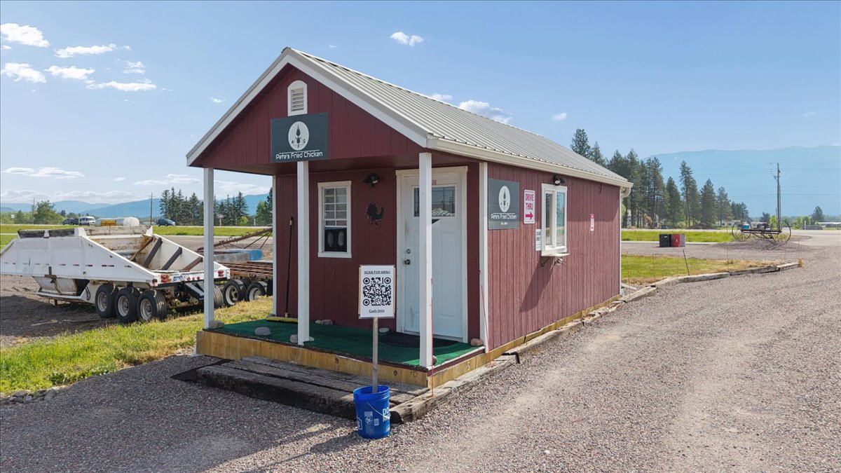 Red-sided commercial building featuring a white metal roof, a white-framed drive-through???????????????????????? window