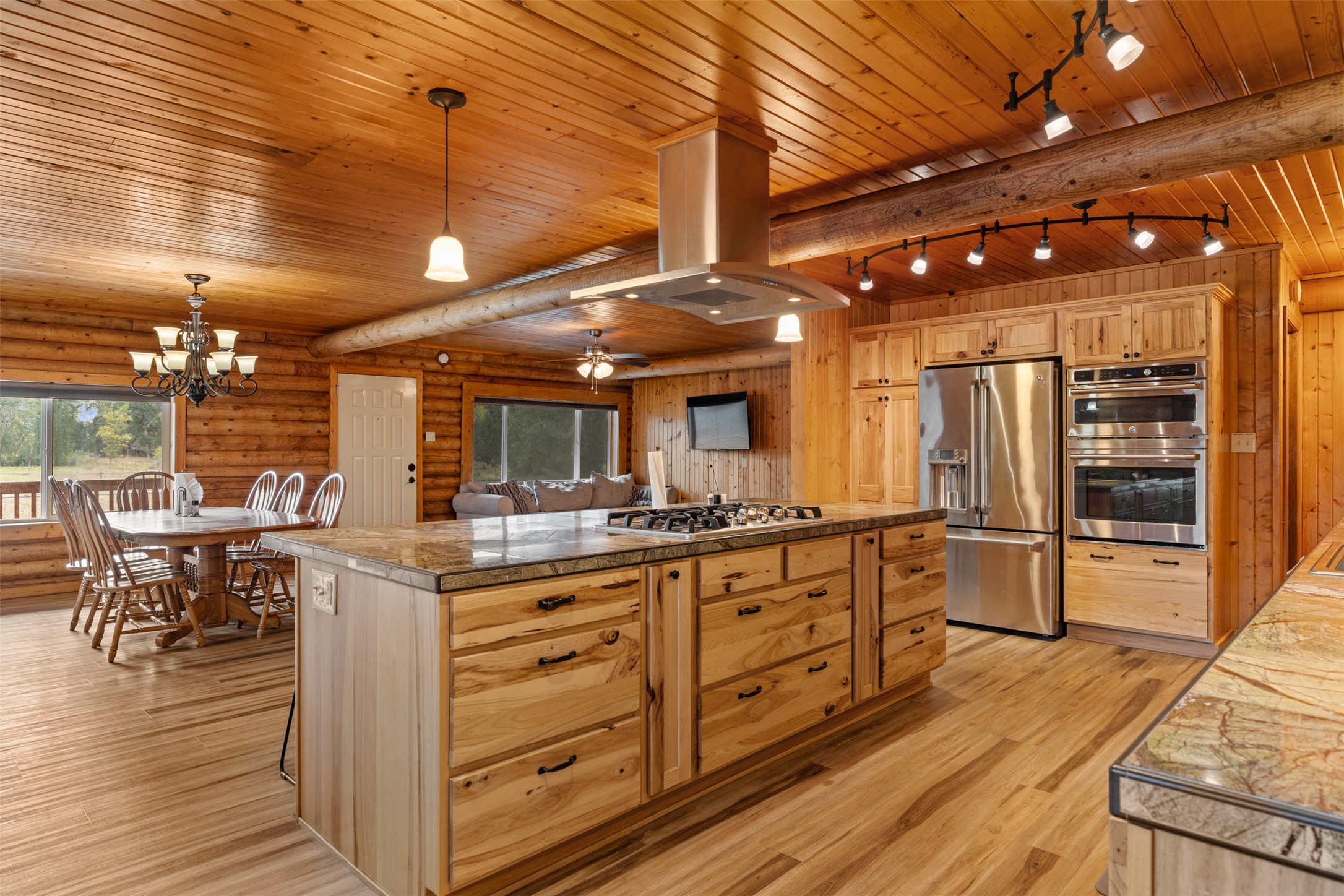 Kitchen with tile countertops, stainless steel appliances, a ceiling fan, a wood ceiling with exposed beams, and island range hood