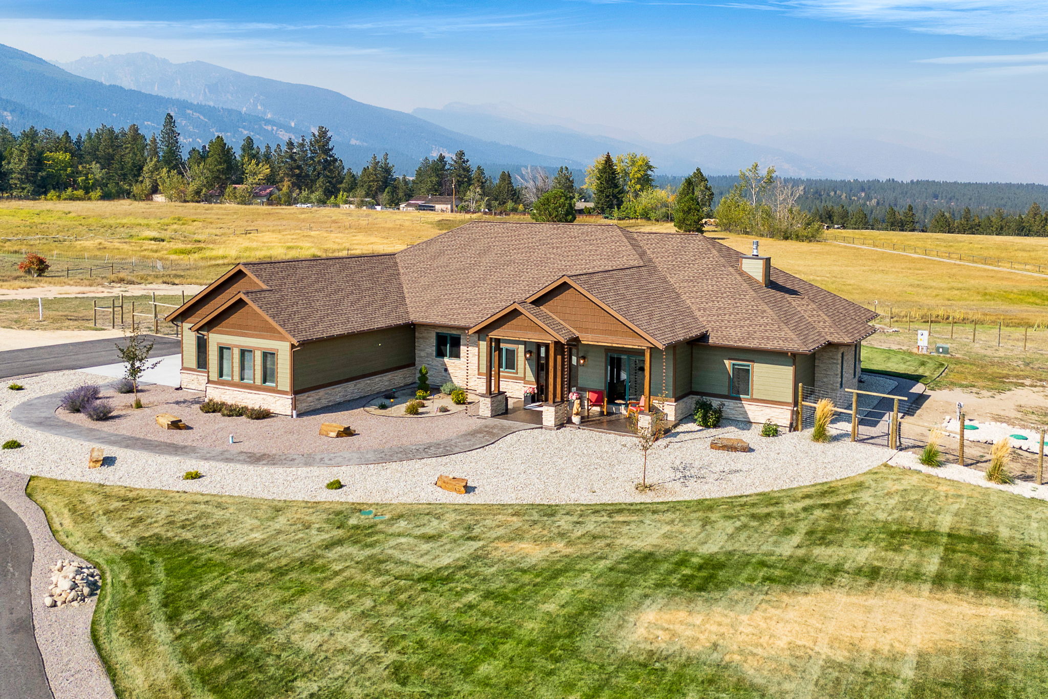 Craftsman inspired home with stone siding, a view of rural / pastoral area, a shingled roof, a mountain view, and a chimney