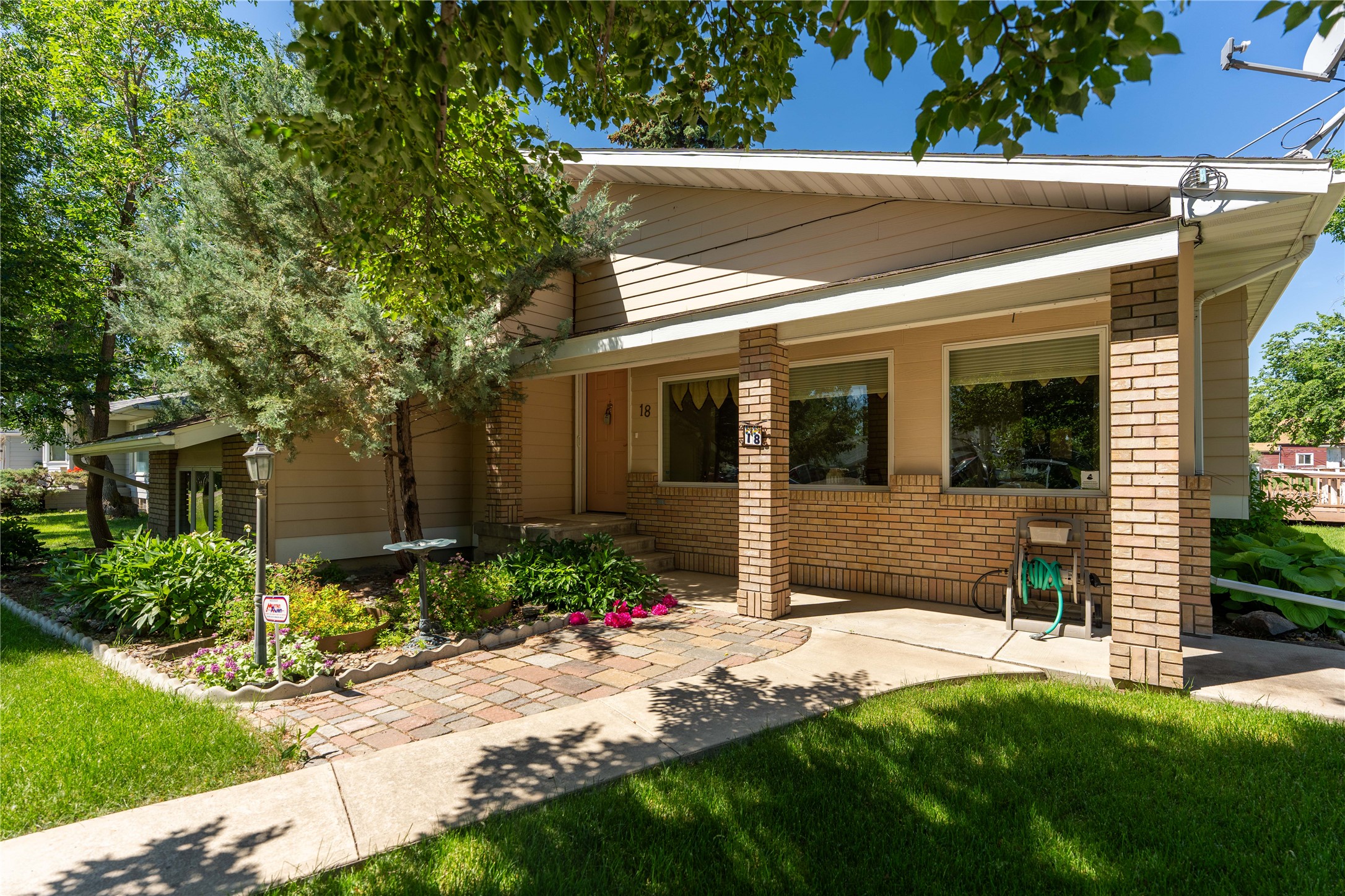 View of front of house with a front yard, brick siding, covered porch, and a shingled roof