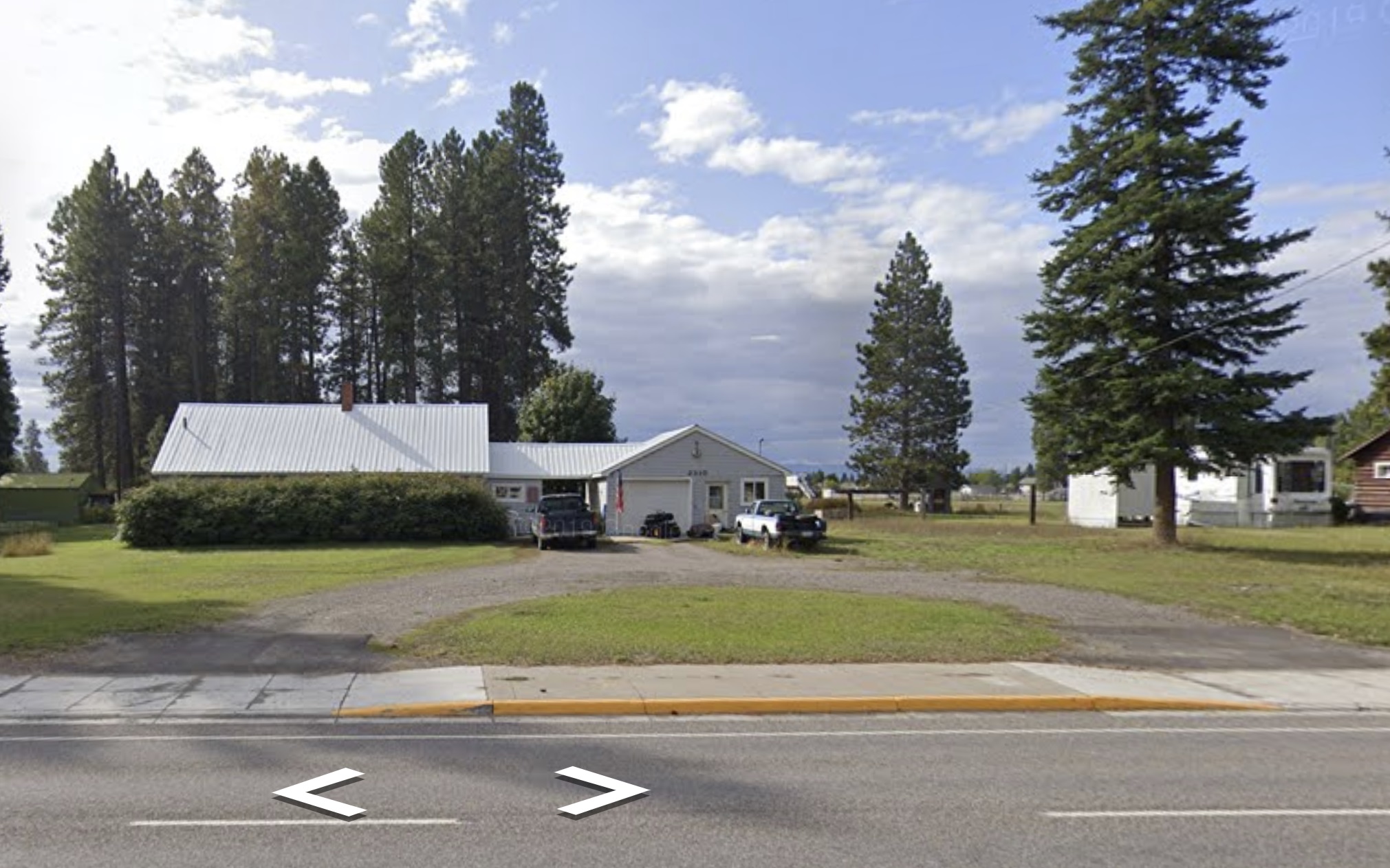 Ranch-style home with an attached garage, metal roof, a front lawn, and curved???????????????????????? driveway