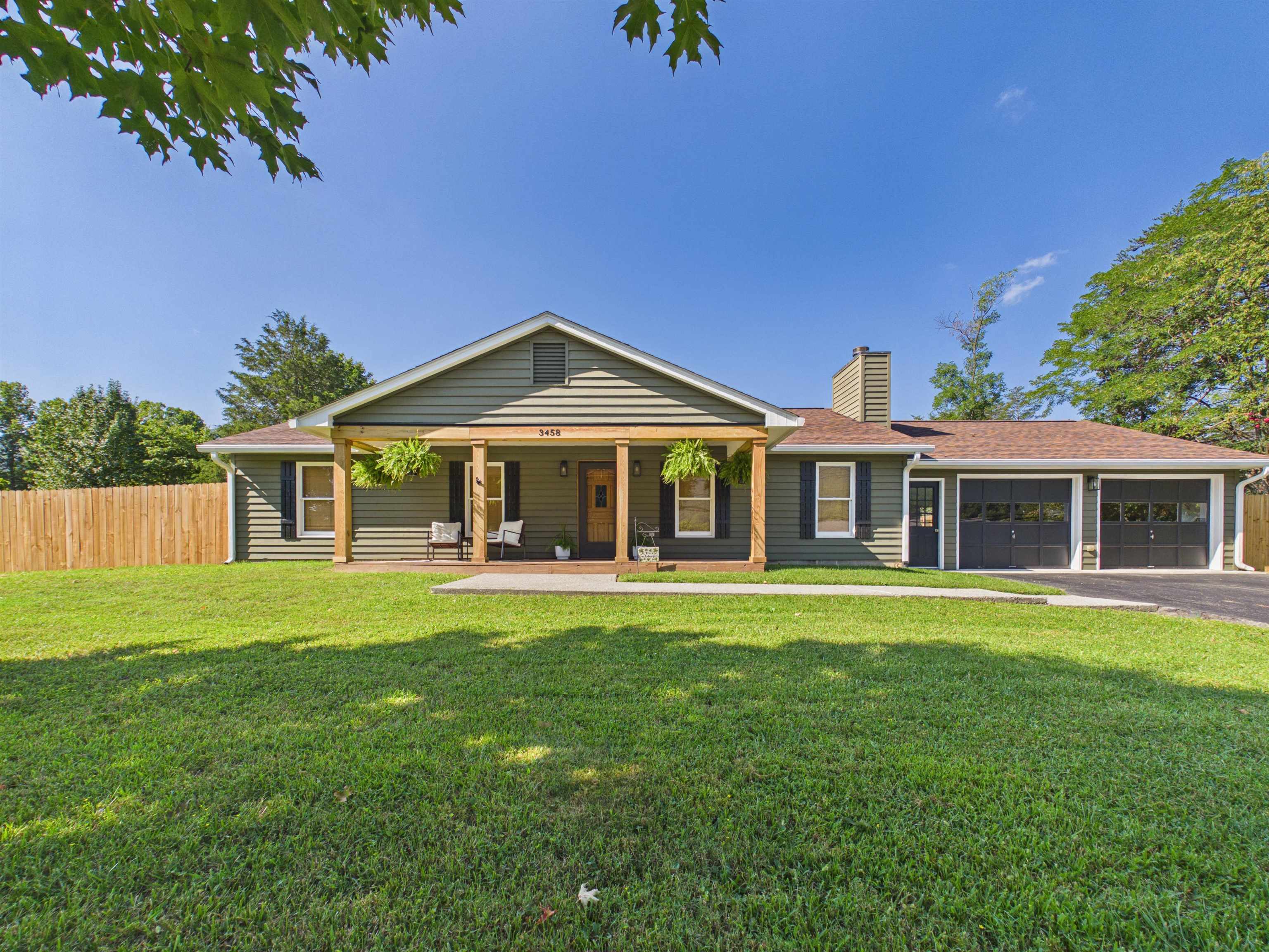 Gray single-story house with a covered porch, hanging plants, and an attached two-car garage.