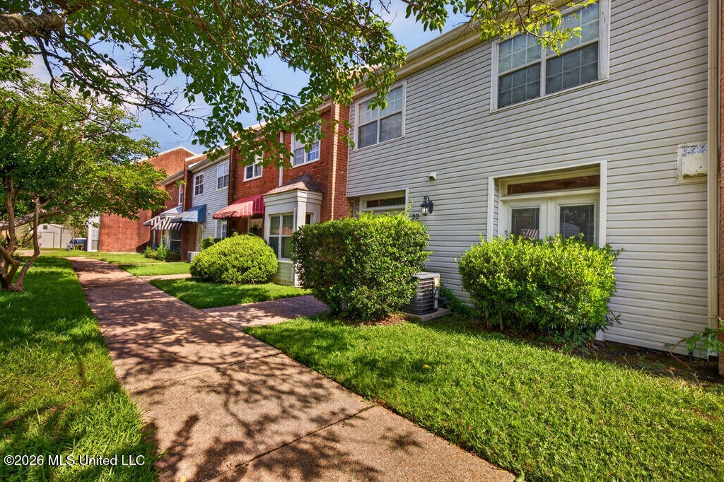Exterior side view showcasing the townhome row, green space, and landscaped common area.