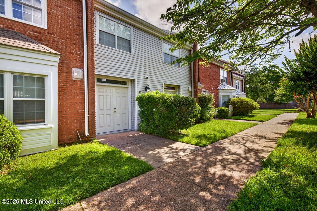 Angled front exterior view showing the walkway, mature trees, and attractive curb appeal.