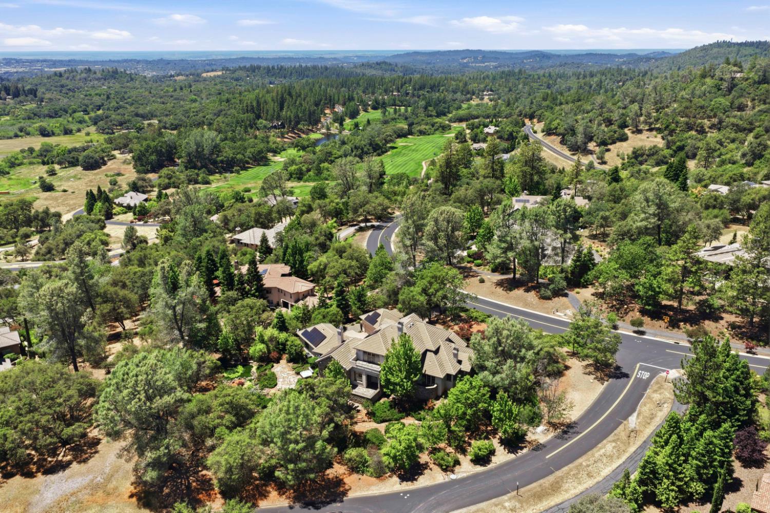 Aerial view of Meadow Vista homes among wooded hills, winding roads, and a green fairway.