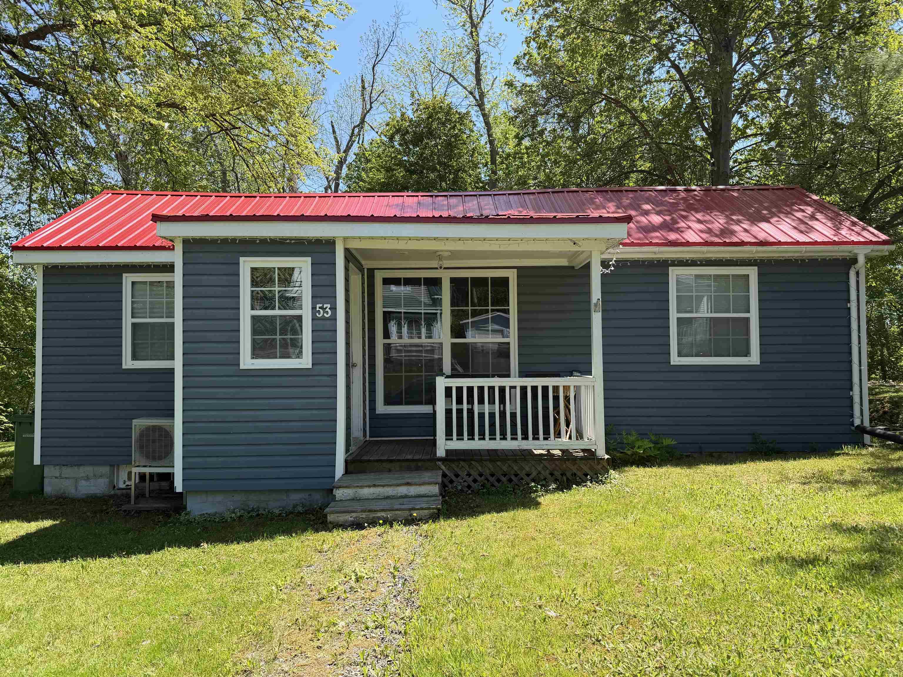 Exterior featuring a prominent red metal roof, gray horizontal siding, and white trim accents