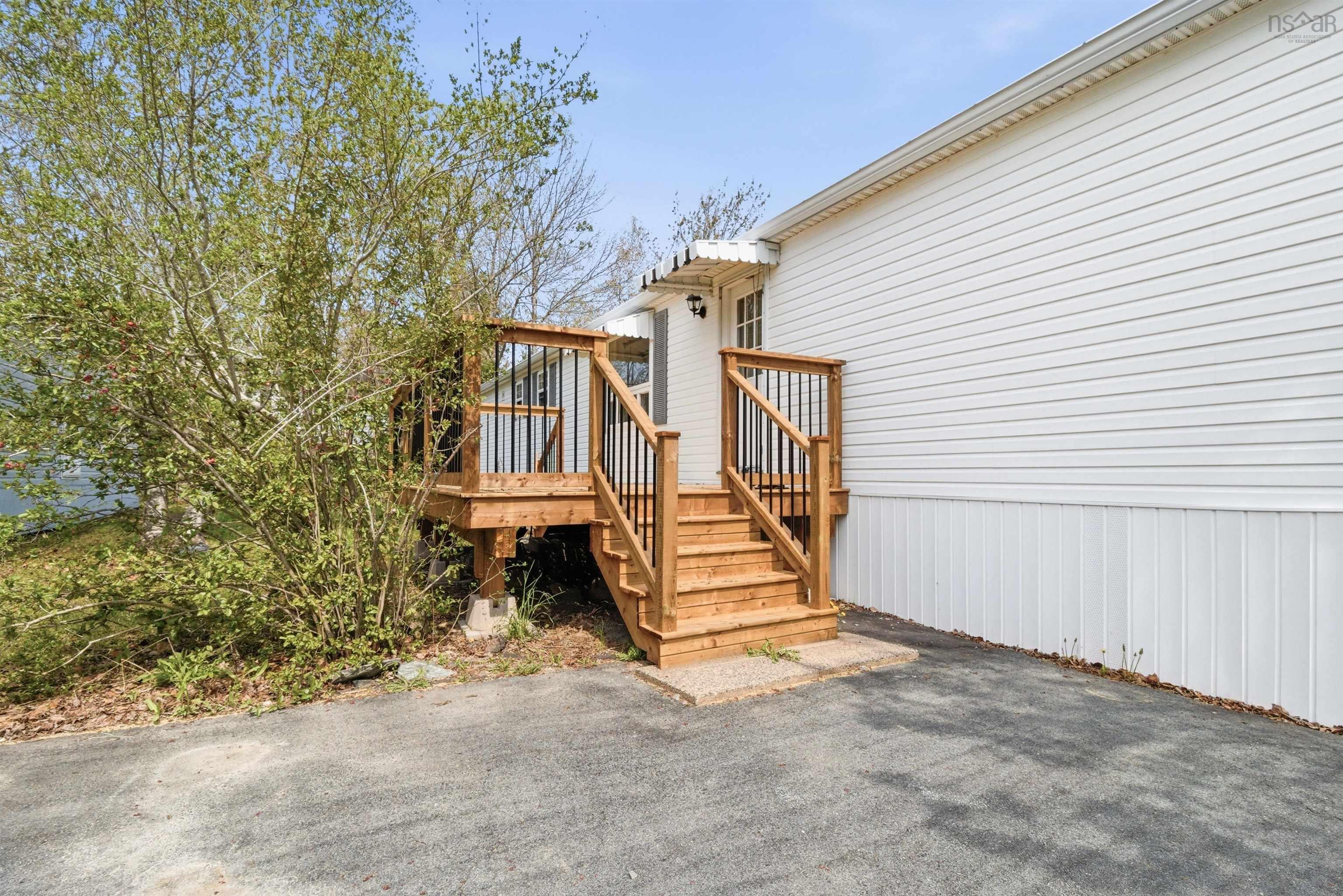 Wood-finish deck with black metal balusters, leading to an entry door with an awning