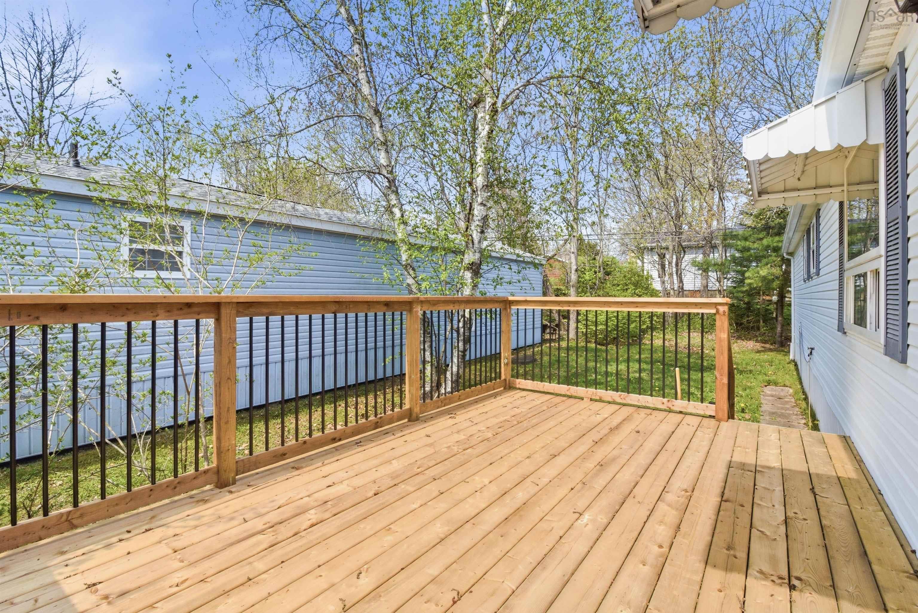 Outdoor deck featuring natural wood planks and a railing with black metal spindles
