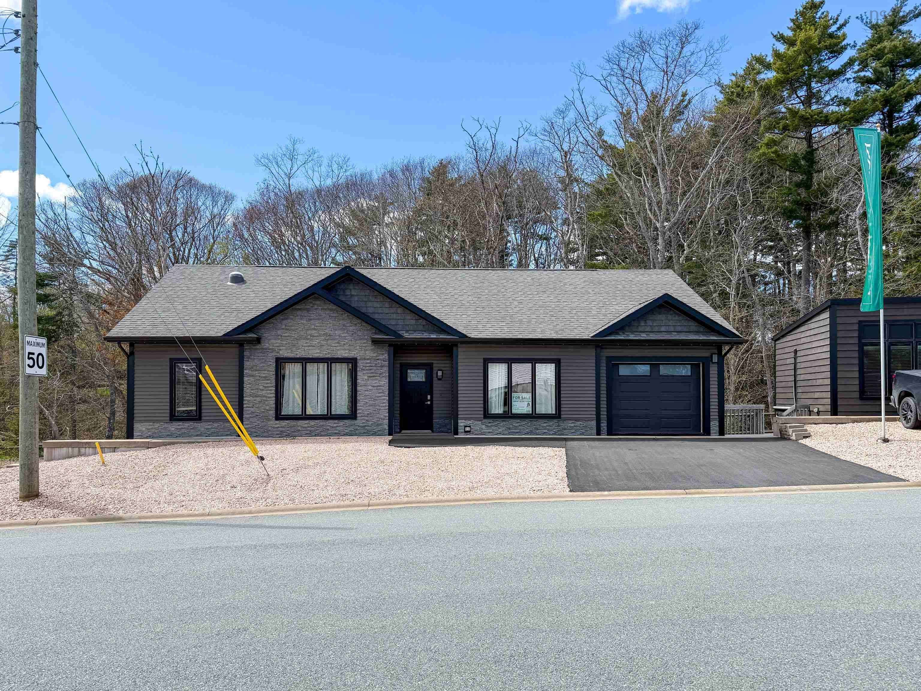 Modern ranch-style home featuring a dark gray shingle roof, stone veneer accents, dark siding, an attached single-car garage with a dark door, and a paved driveway
