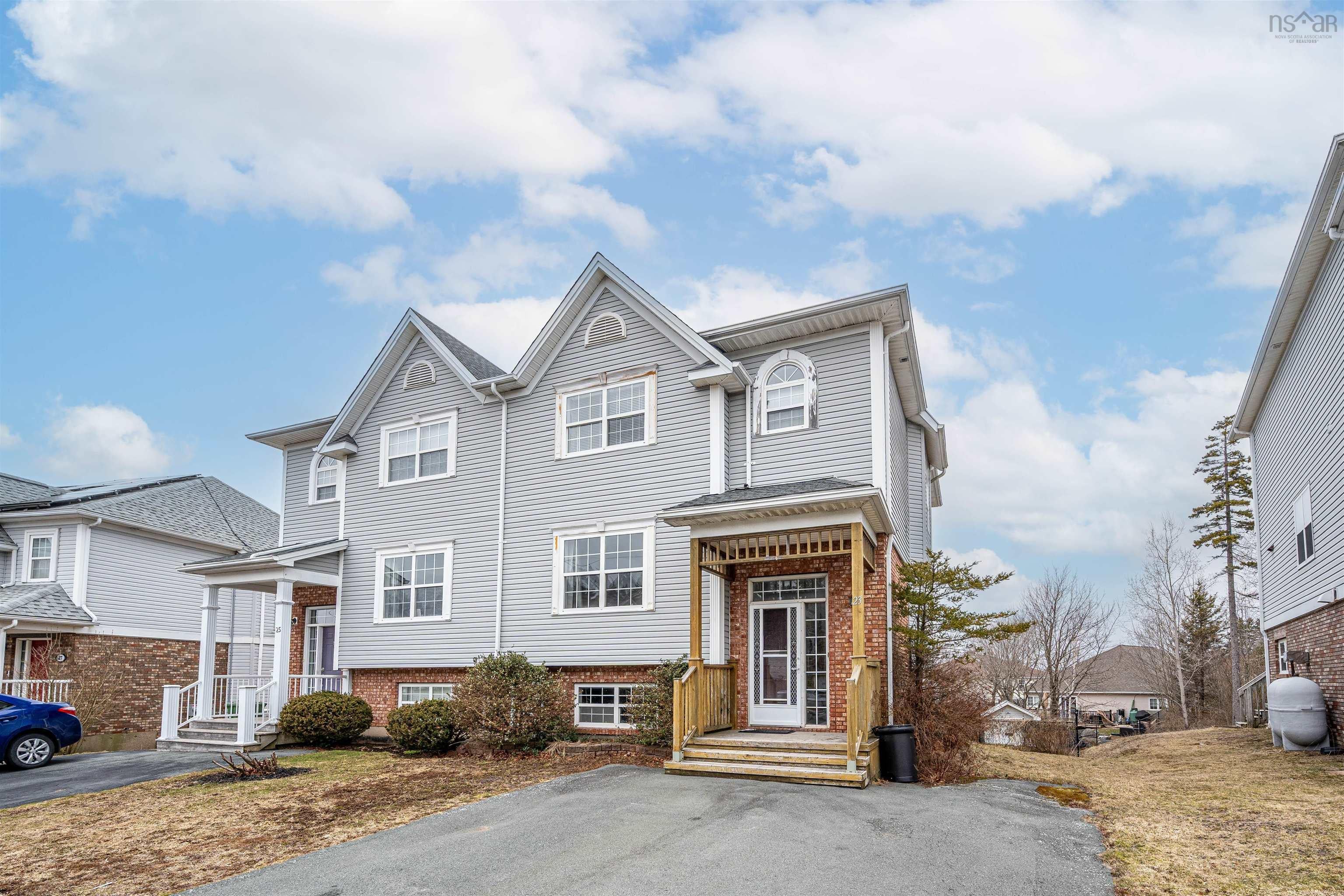 The property features a multi-story exterior with light gray siding and a brick base
