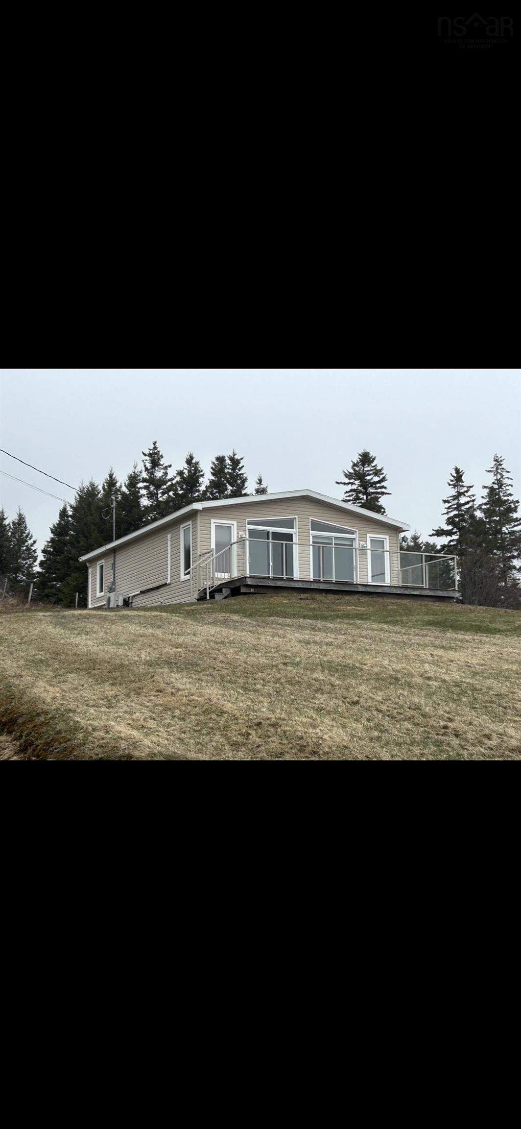 The property features a spacious deck, multiple large windows, and an expansive lawn