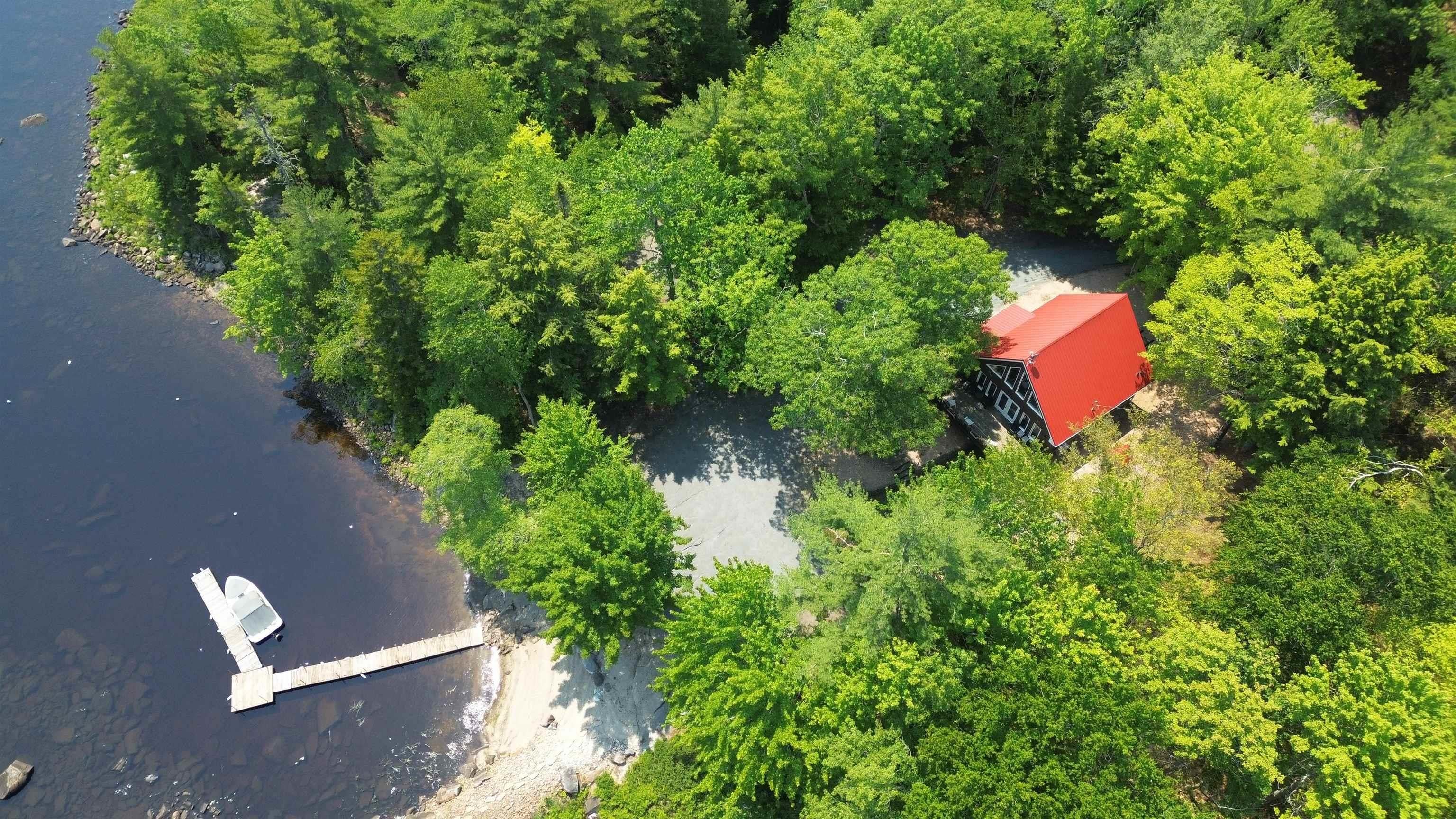 Waterfront property featuring a private dock, sandy shoreline, and wooded surroundings