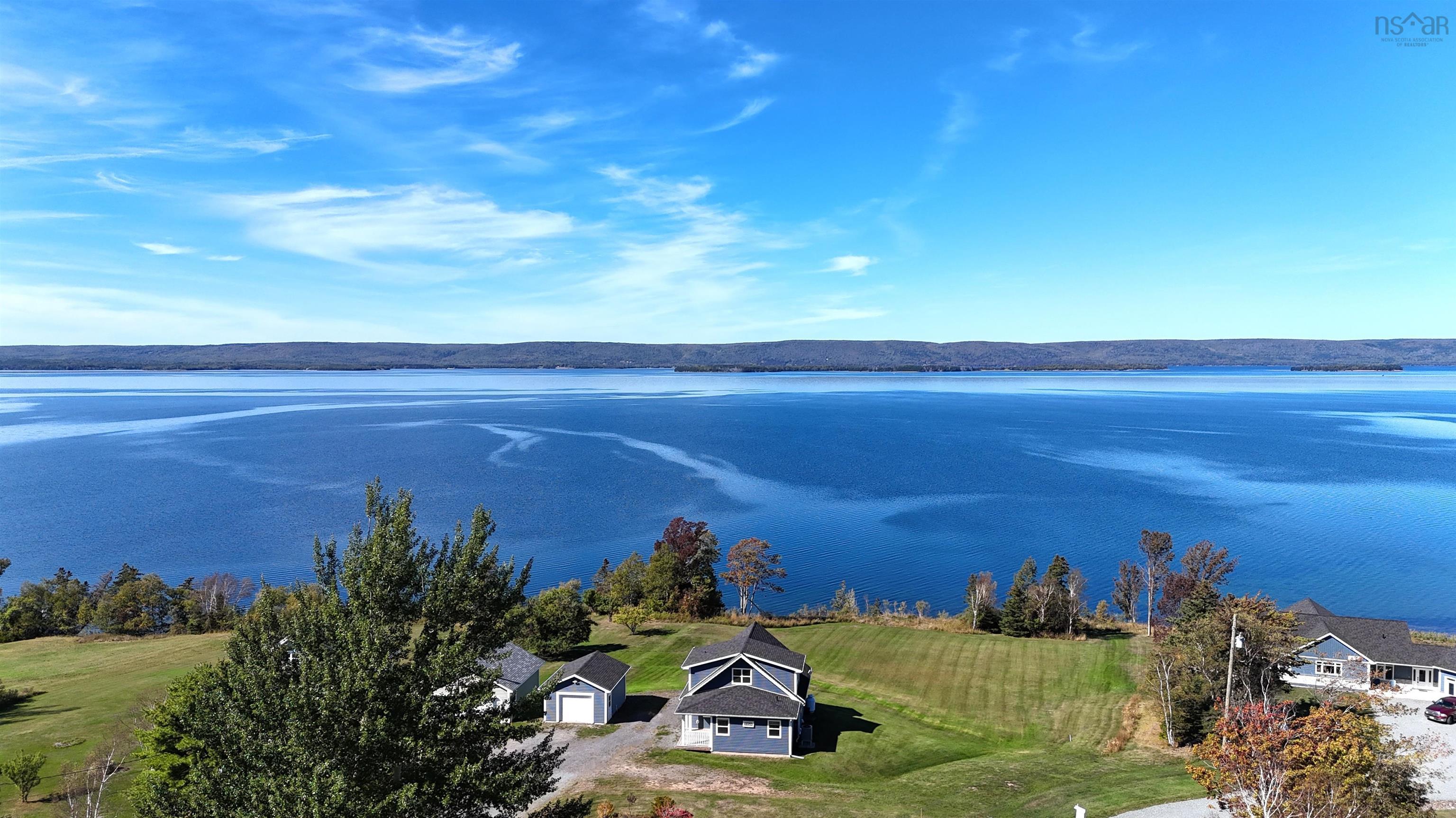 Aerial perspective featuring a waterfront property with a gray-sided residence and a detached garage