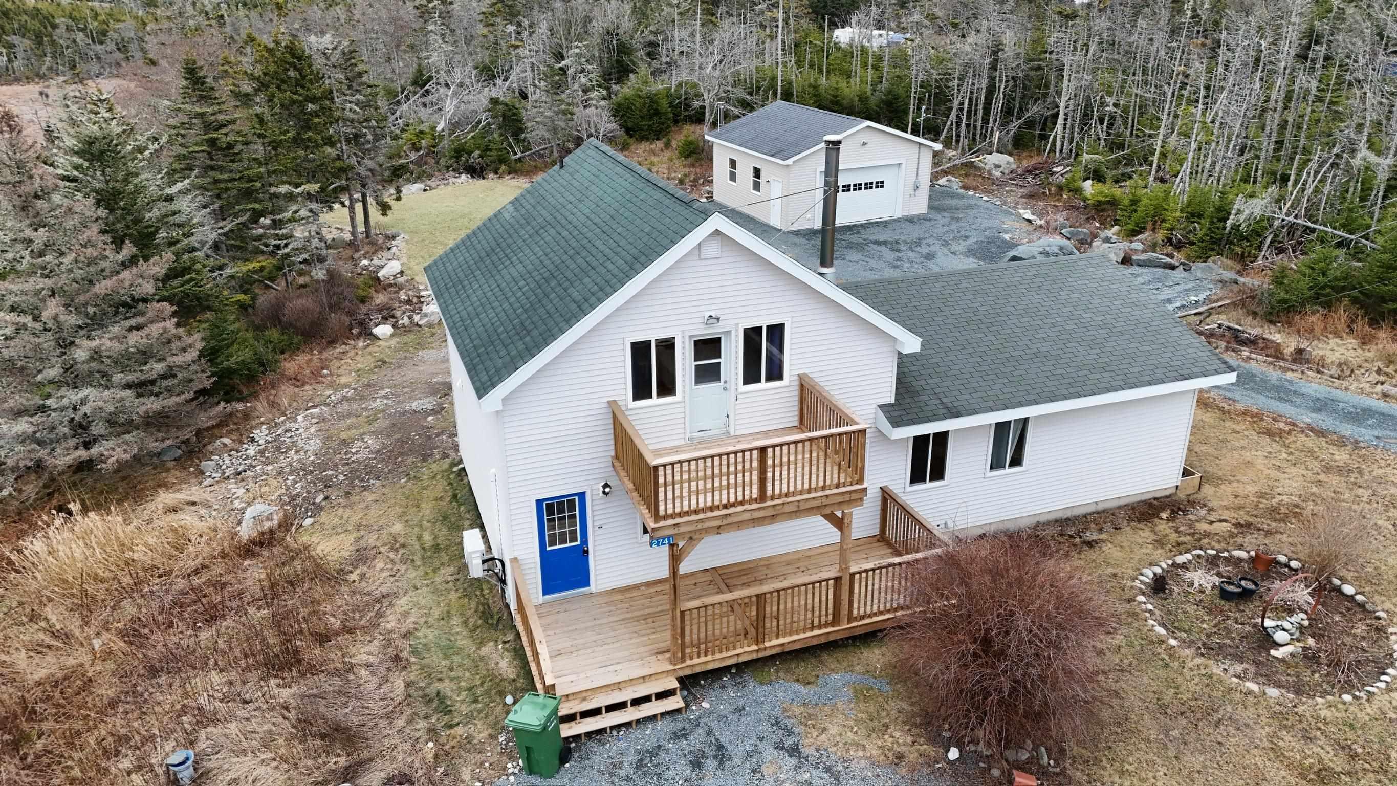 The property features a two-story deck, a white exterior, and a dark green shingled roof